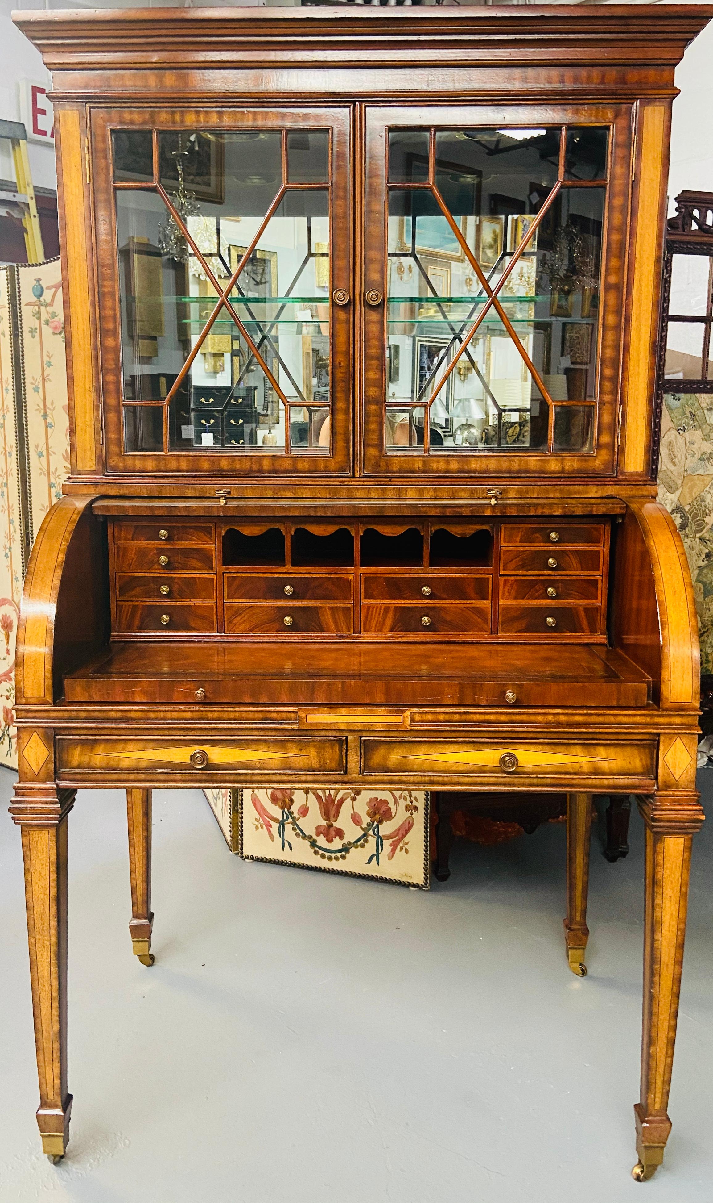This stunning Regency style Maitland Smith flame mahogany secretary desk has two parts. The upper part is a two sectional glass door cabinet with one glass shelf and two adjustable inside lights. The bottom part features a slant lid covering