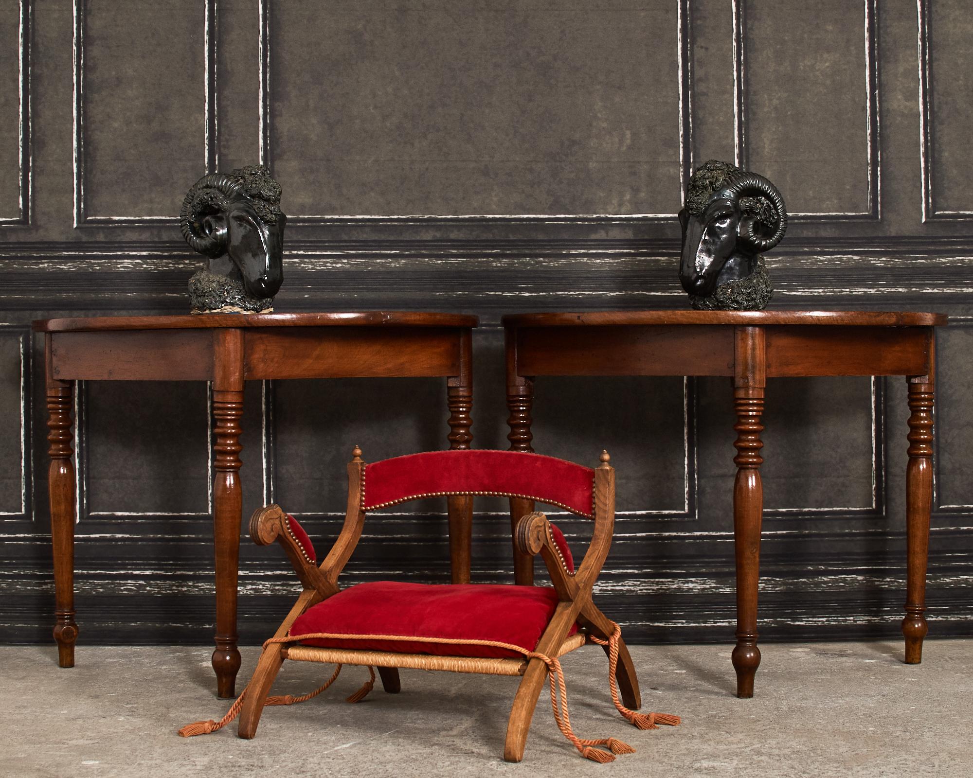 Diminutive camel or elephant saddle stool or armchair crafted from oak in the regency taste. The hardwood oak frame features an x-form curule leg construction. The arms have scrolled, reeded hands with padded rests. The gracefully curved back has