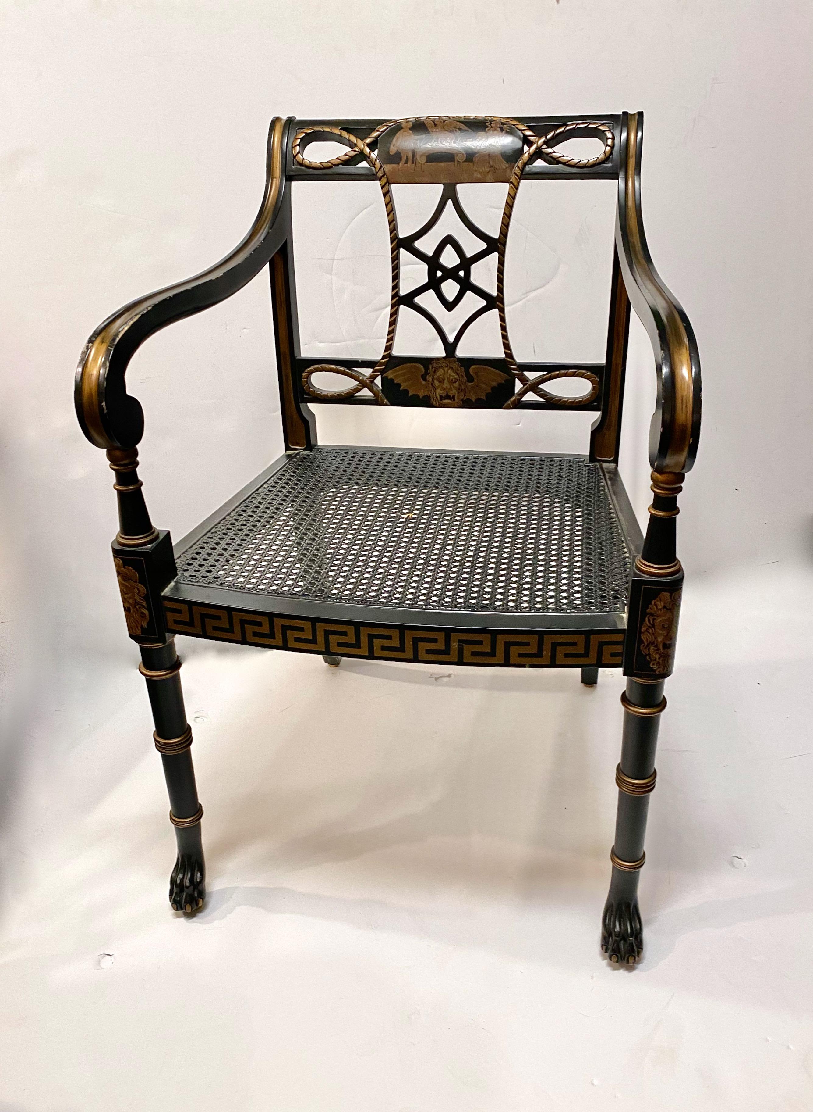 This is a chic Regency-style open arm chair that dates to c.1950-1960. The chair features black lacquer detailed in gold, well-carved paw feet, faux bamboo and a caned seat. The chair is labeled Interior Crafts Chicago.