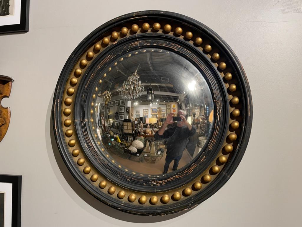 Great looking round bullseye mirror with dark green, almost black, paint with an interior gilt molding with carved wood orbs. Classic English Regency style bullseye convex mirror with concentric circular molding. I love the original paint with