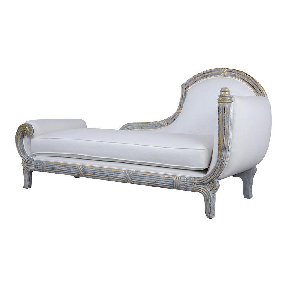 This 1970s Cleopatra style chaise lounge has been newly painted in a grey and off-white color combination with a distressed finish. It features carved details on the frame, original gilt accents with a distressed finish, and a long single foam