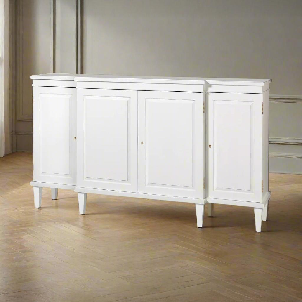 Painted credenza commands attention with its elegant breakfront form and refined classical details. Finished in Benjamin Moore's White Dove, the crisp surface accentuates the symmetrical paneled doors and architectural moldings, while brass key