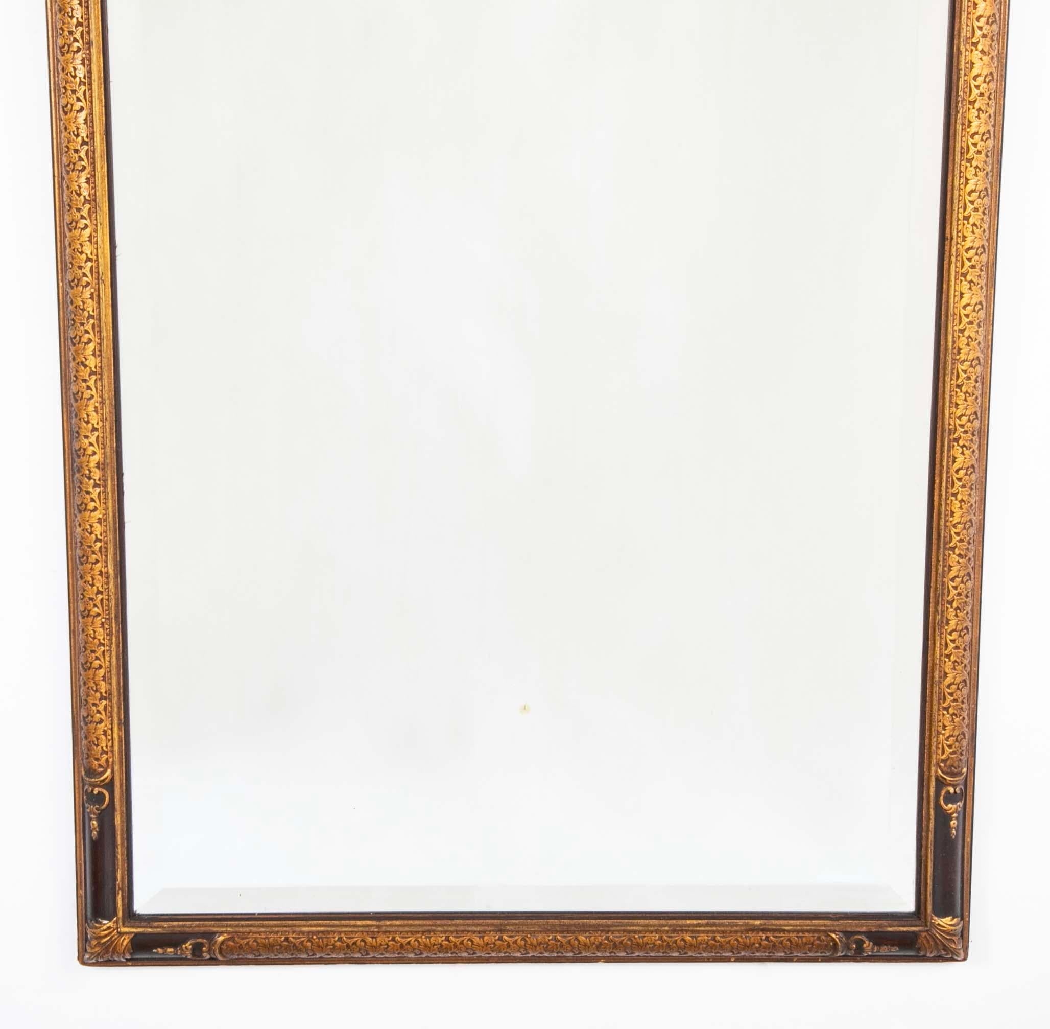 Espejo de pared de estilo Regencia con decoración floral en relieve y gesso dorado. Conserva el cristal biselado original. El marco de nogal está pintado de un marrón chocolate intenso que contrasta maravillosamente con el dorado apagado. 
Esta