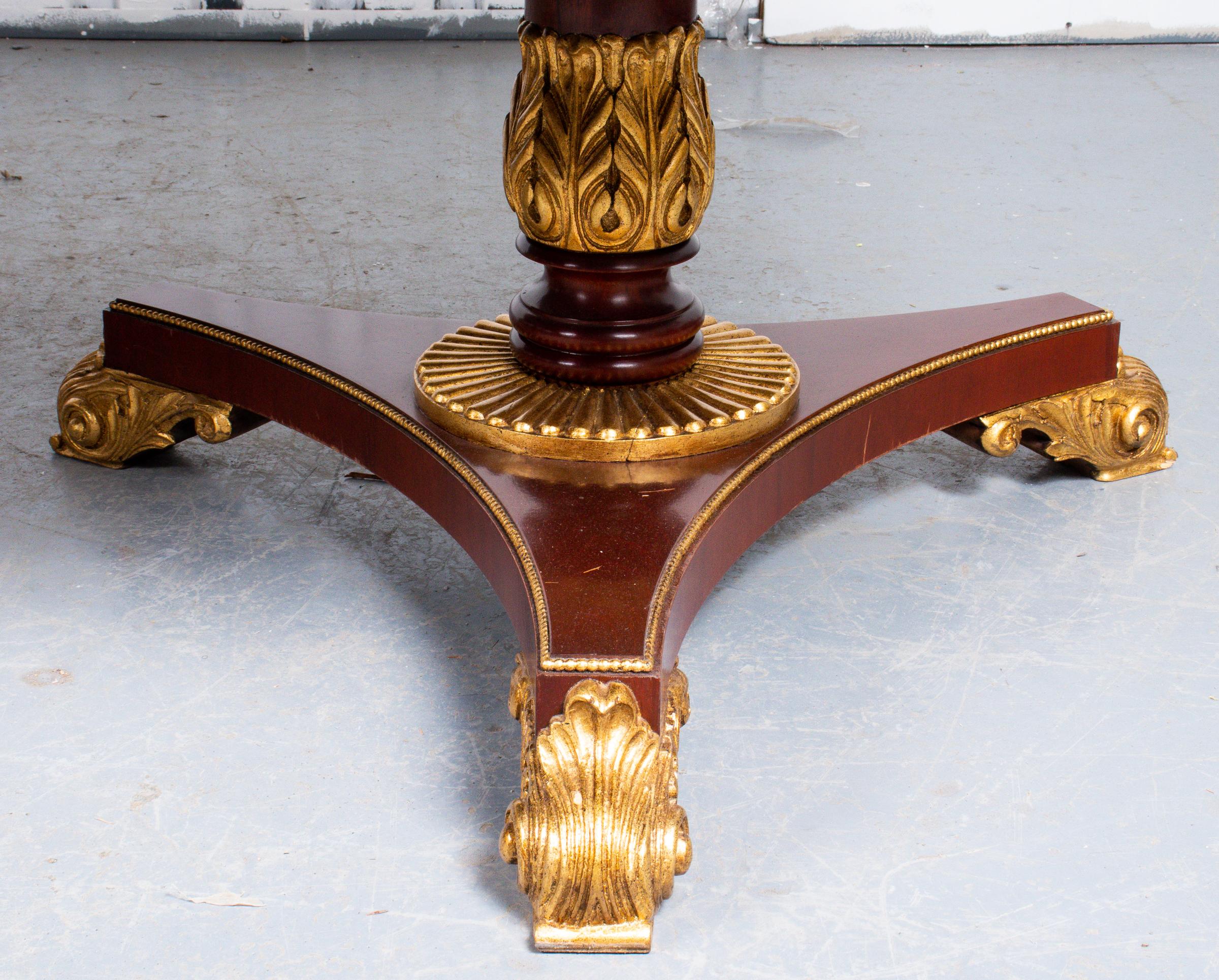 Regency style mahogany extension dining table, the top with banded border, the two pedestals with parcel gilt acanthus motif details to the supports and feet, with three leaves. Measures: 28.5” H x 46” W x 72” D, each leaf 16