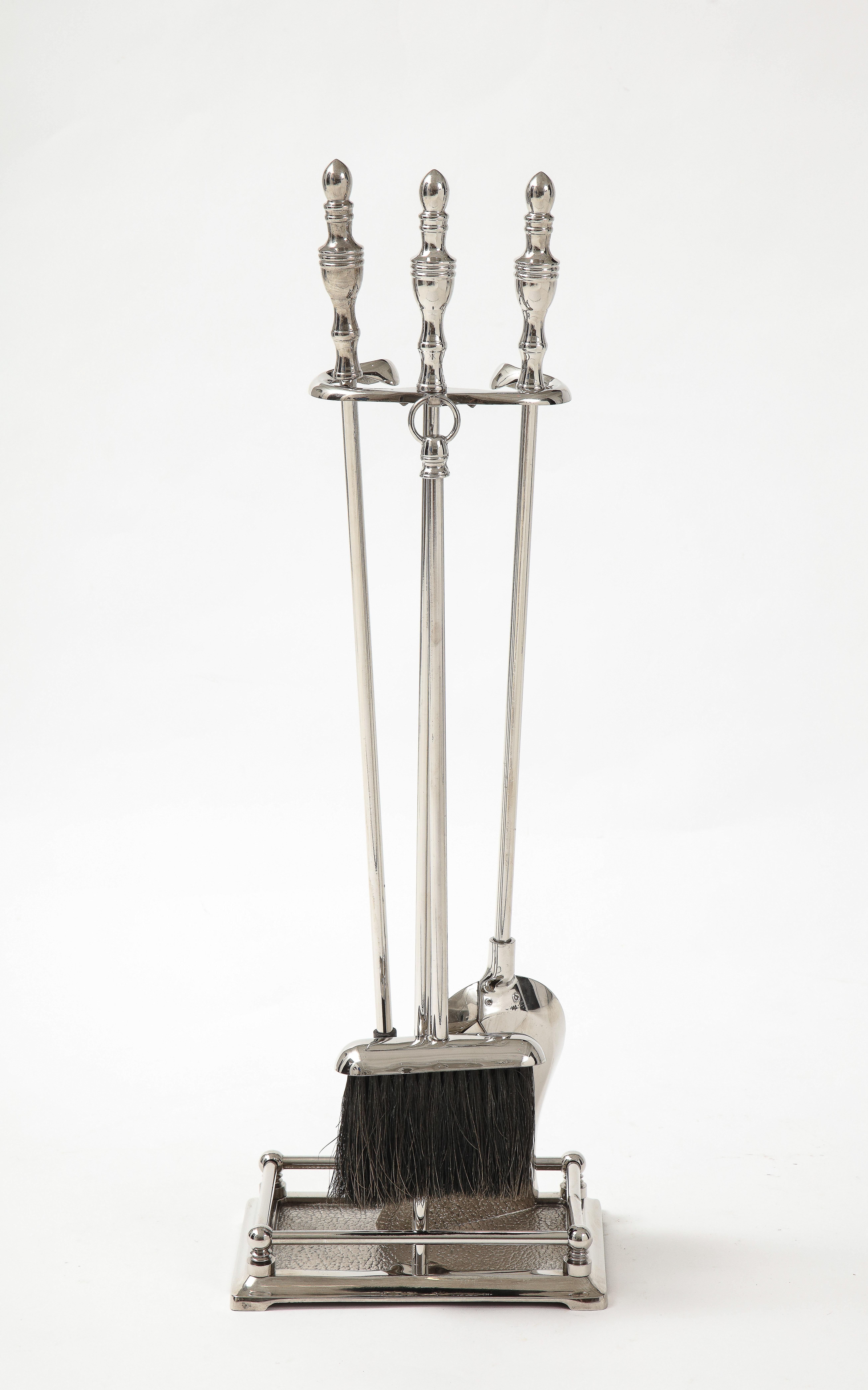 Set of Hollywood Regency polished nickel firetools with stylized spire handles. Set includes stand, poker, broom, and shovel.
