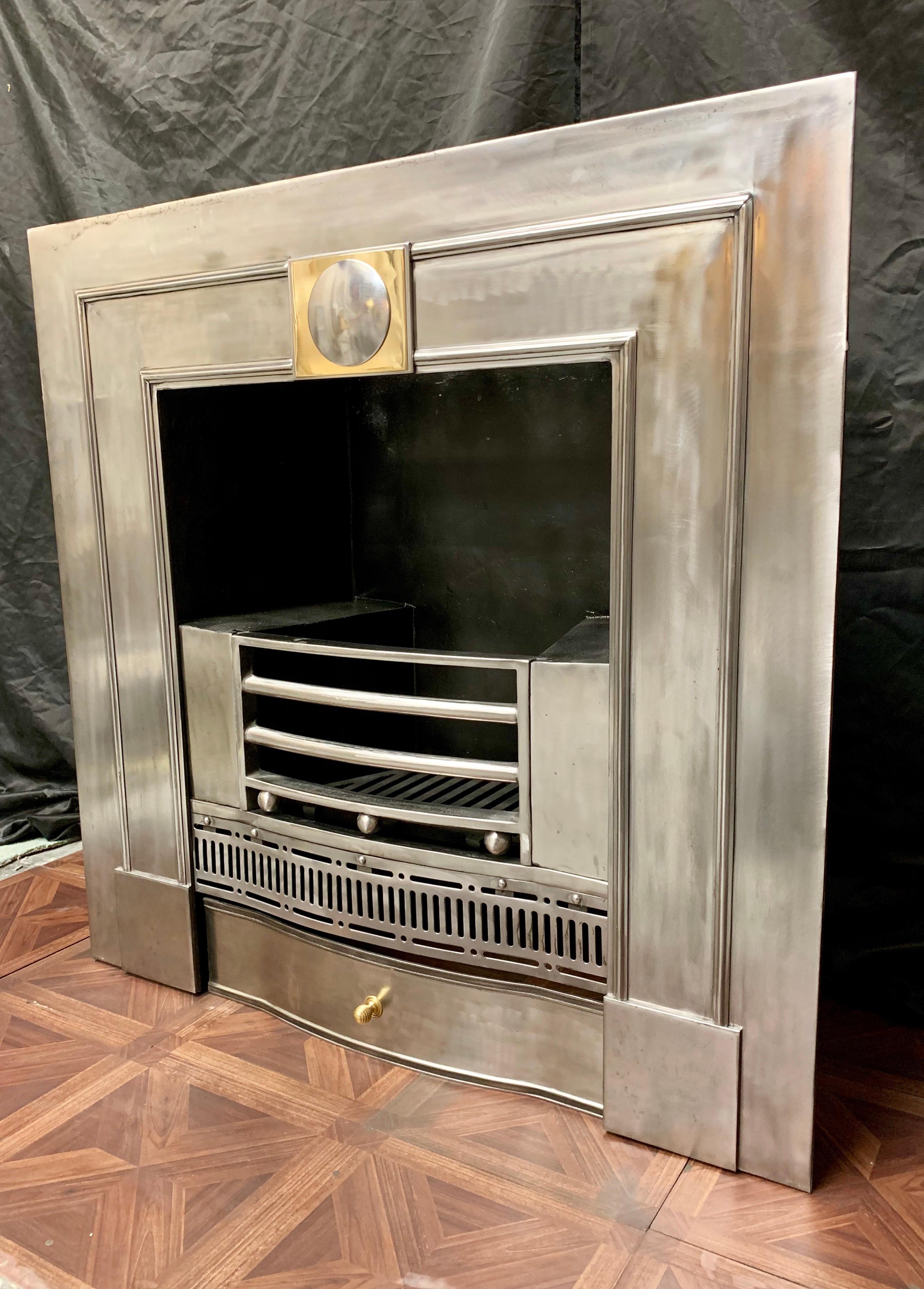 A medium Regency style polished steel register fireplace grate of handsome proportions. A removable four barred fire grate with three ball spacers above a serpentine pierced steel apron, below a shaped ash pan cover with beehive handle. The central