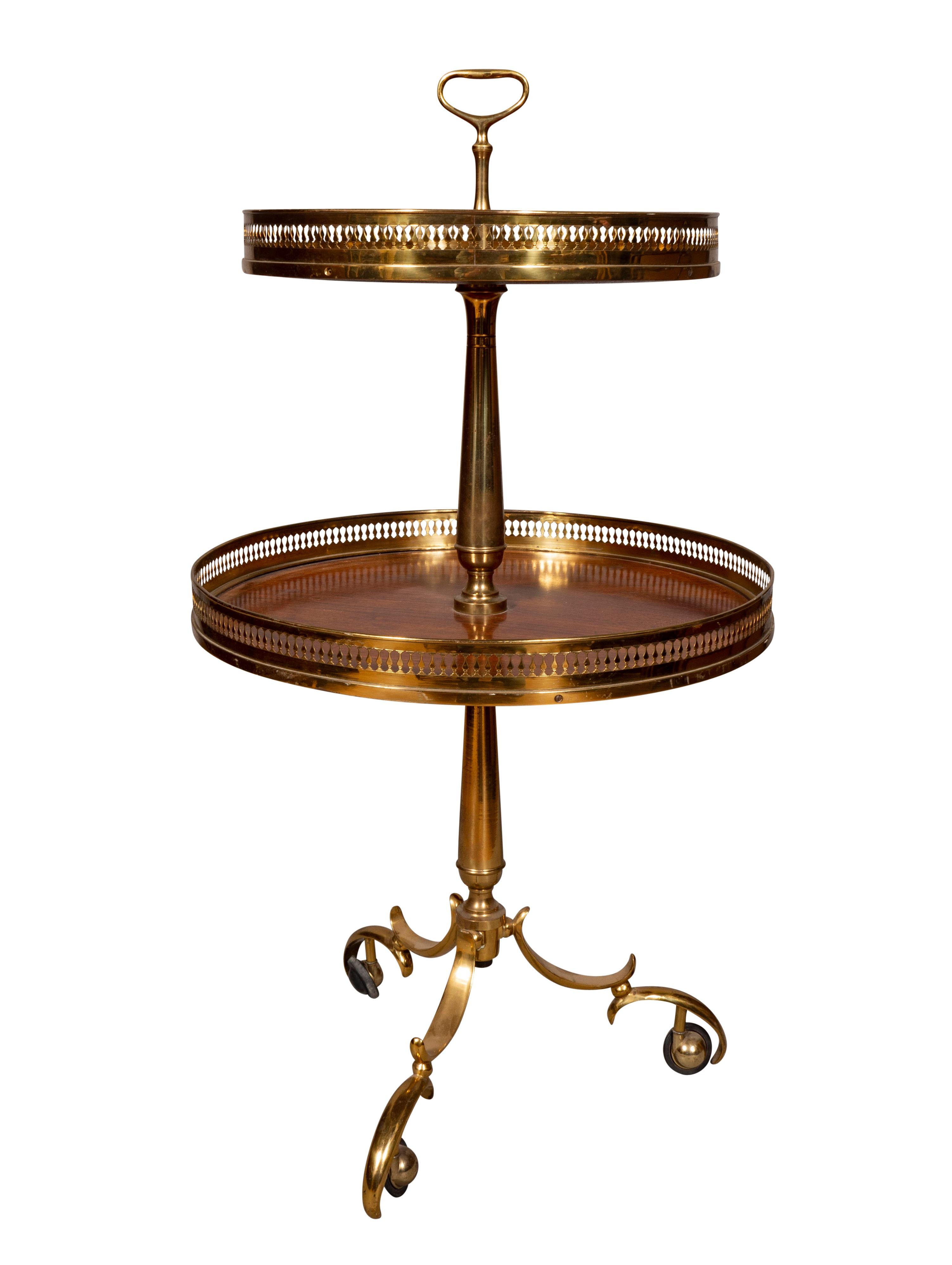 With handle finial over two tiers with brass galleries and raised on a brass tripartite base with scroll legs.
