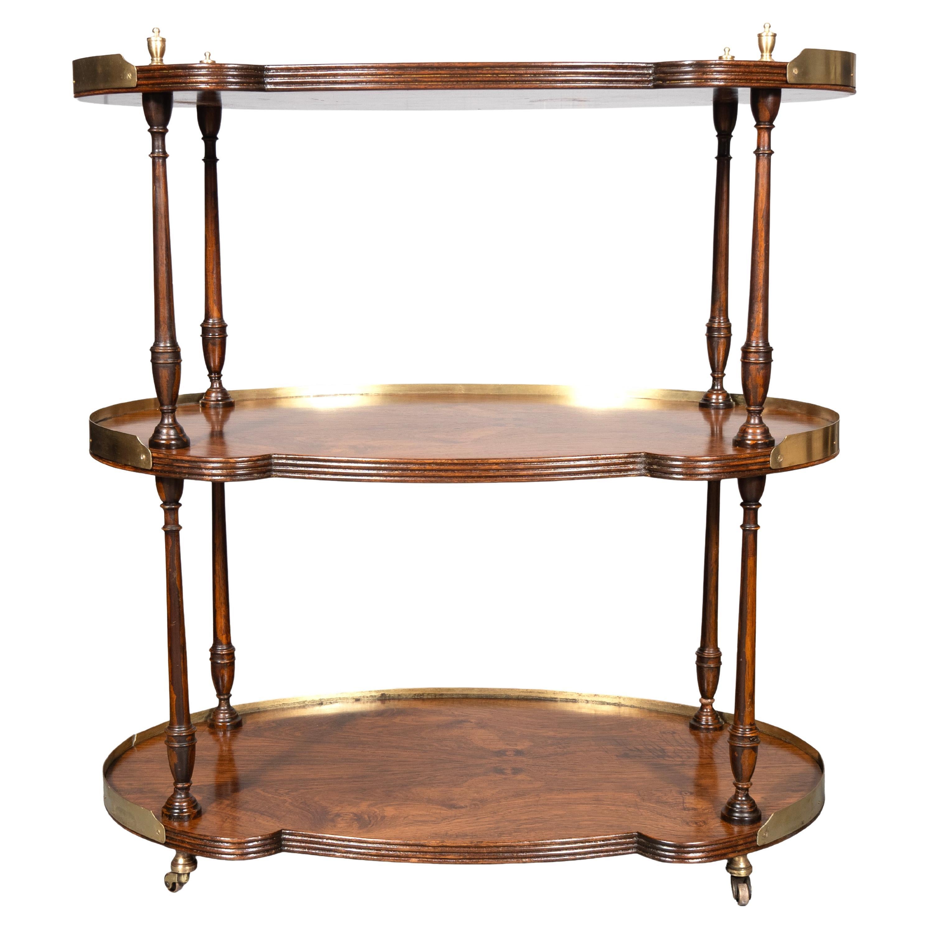 The finest quality with solid rosewood spindles. Brass finials. Three shaped tiers with 3/4 brass galleries. Brass casters. Likely Smith & Watson. Excellent condition for a used piece.