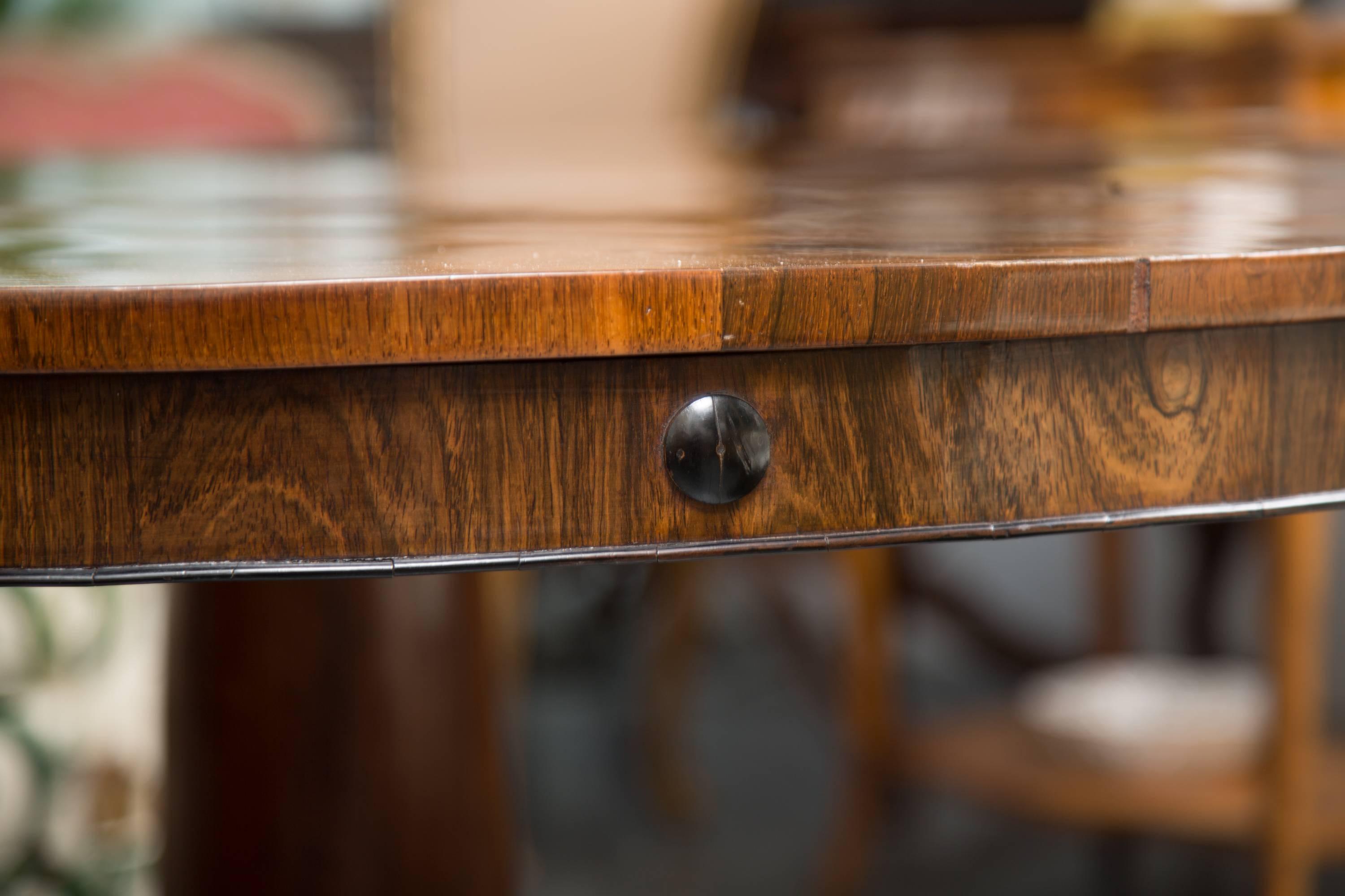 This stately and sophisticated rosewood centre table represents the Regency Period as a stylish and substantial focal point in any fine interior setting. The beautifully mirror-grained top with straight edge above a slightly recessed frieze is