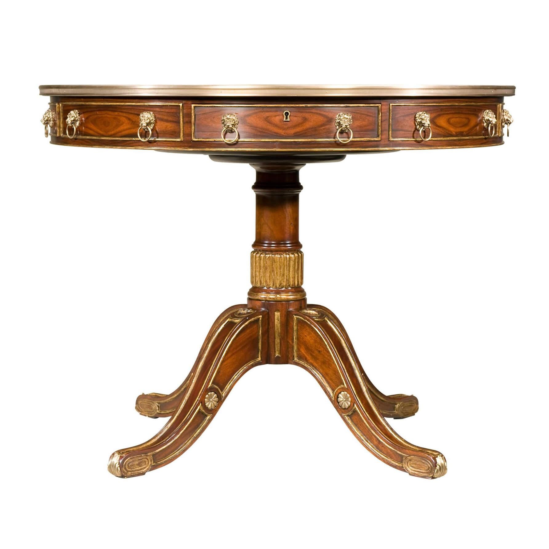 A rosewood and parcel gilt drum top table with mahogany crossbanding, the circular brass bound top above a frieze with four bowed drawers applied with brass lion mask handles and interspersed by four dummy drawers, on a turned and reeded mahogany