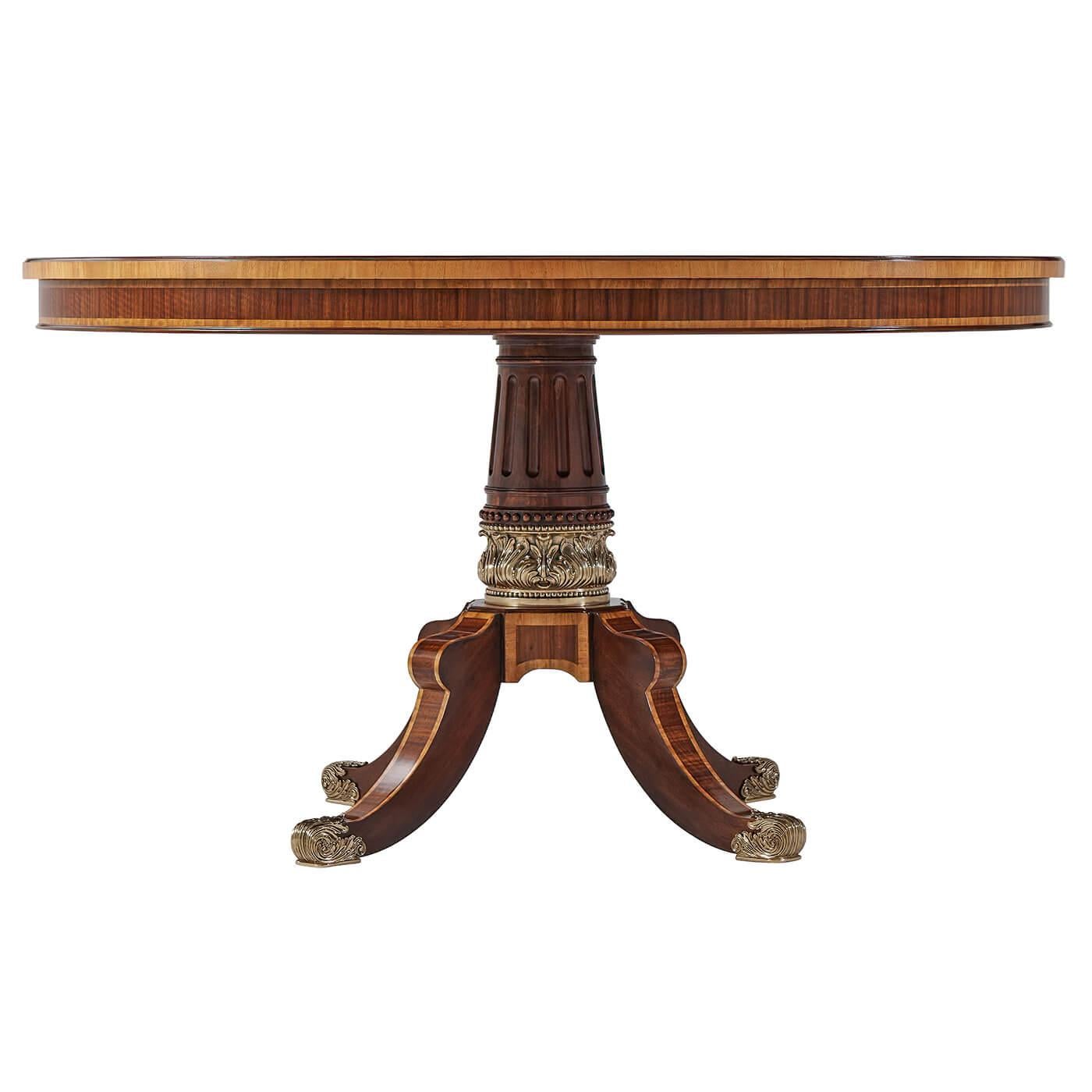 Regency style brass inlaid and crossbanded round dining table with a carved acanthus pedestal base having cast brass accents.

Dimensions: 53.25