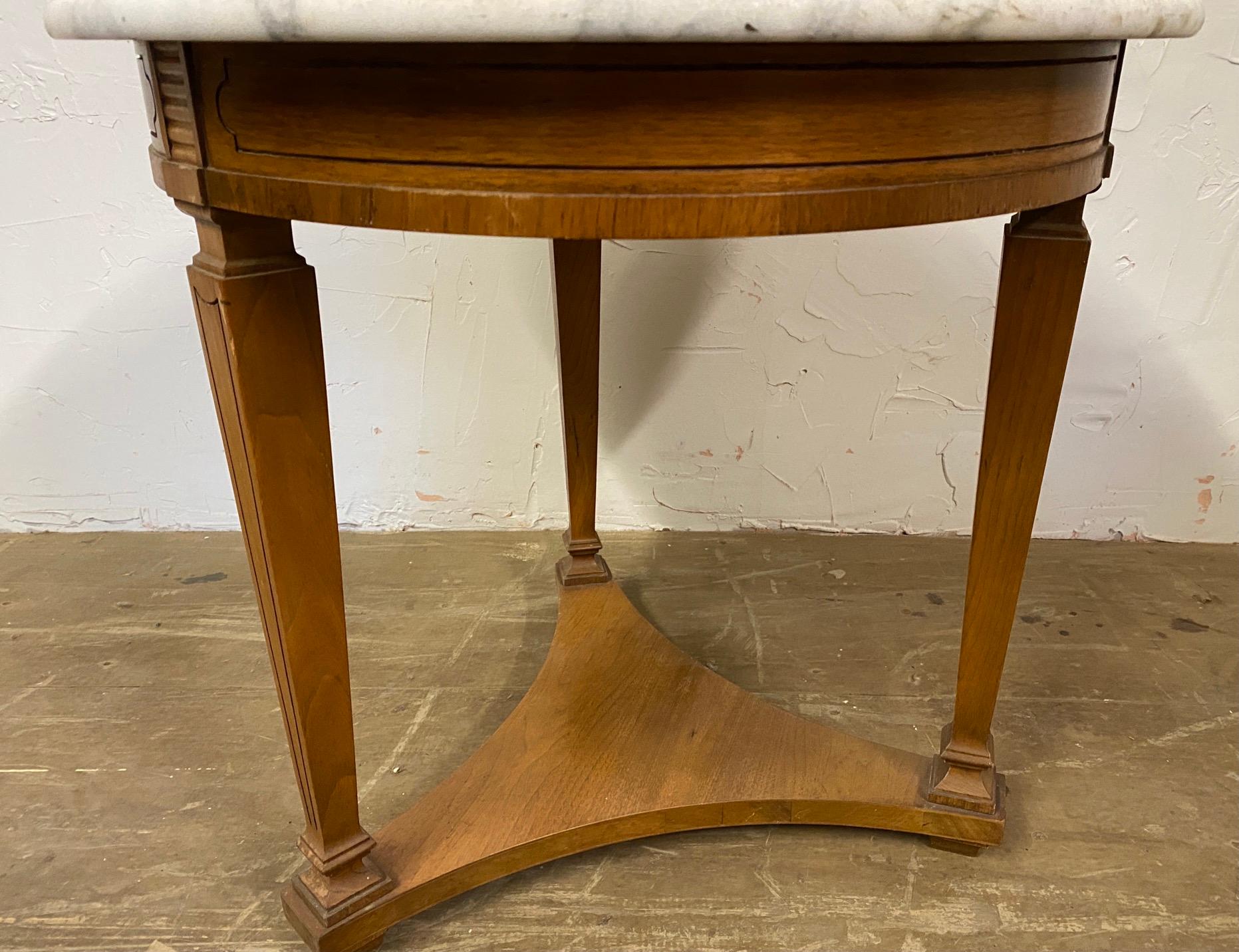 Round Regency style table having a 3 sided triangular stretcher between tapered tripod legs, a beautiful white marble top, and bronze decorative mounts.
End table, round occasioned table, side table, Hollywood Regency.
 