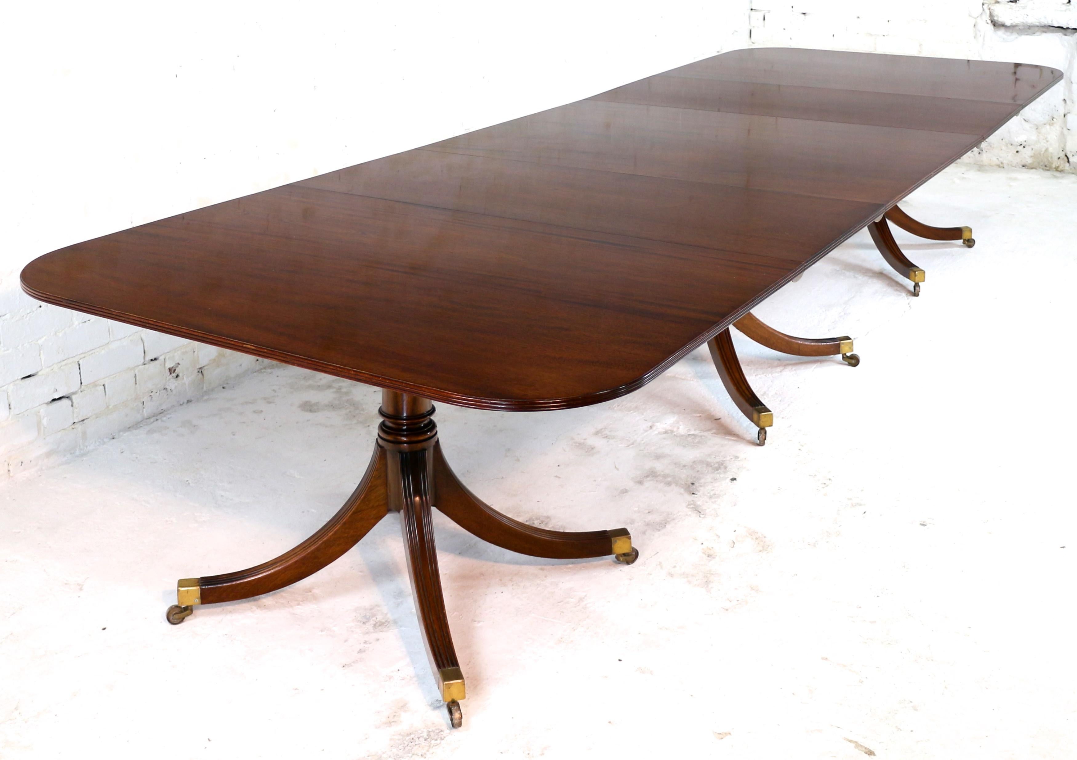 A super quality Regency style three pillar solid mahogany extending dining table by the late master cabinetmaker, William Tillman, and dating to circa 1980. This super quadripartite triple pedestal table has a rounded rectangular top with a reeded
