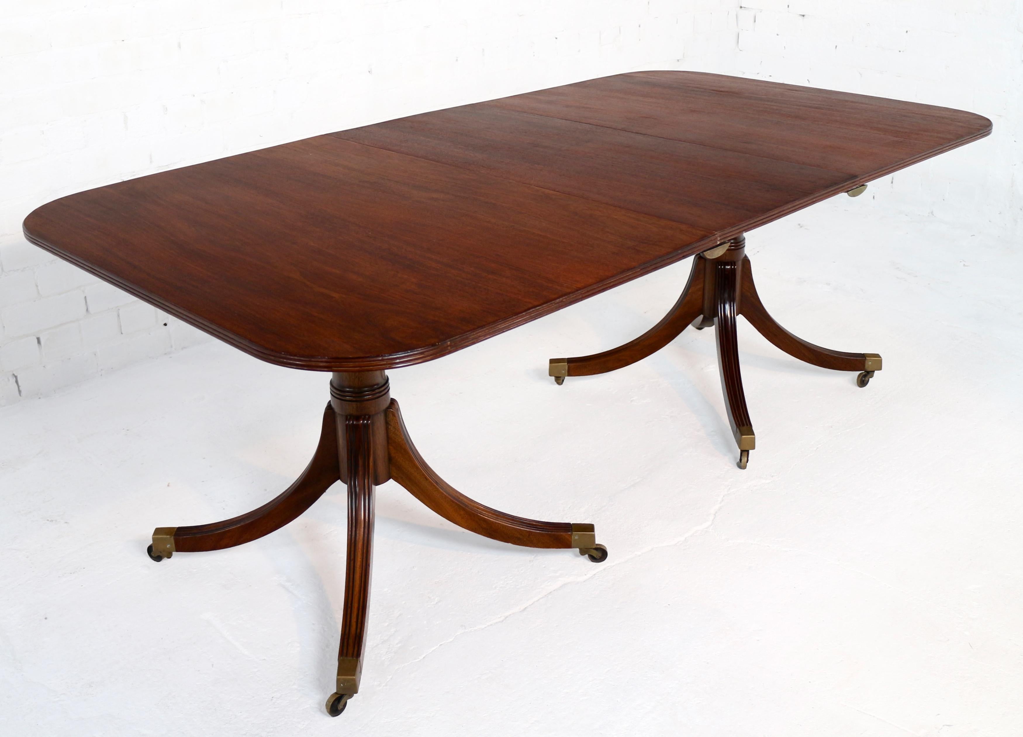 A twin pedestal solid mahogany extending dining table in the Regency taste, English and probably dating to the first half of the 20th century. This lovely examples has the more desirable & stable four legs to the pedestals and can seat up to 8 with