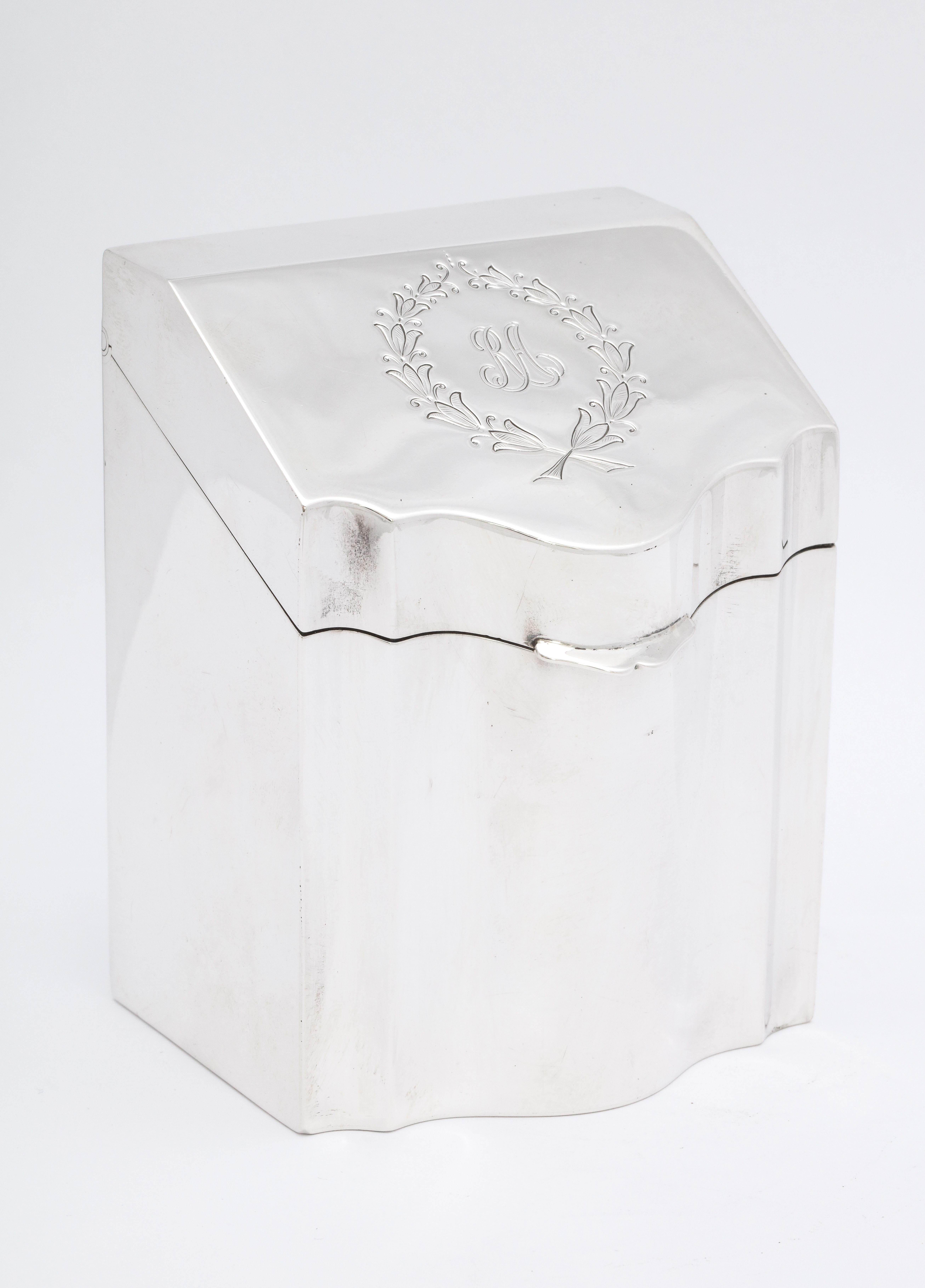 Regency style, sterling silver, knife-box-form tea caddy with hinged lid, American, Ca. 1910. Has a wreath-form cartouche, which is engraved with the script initials RA that look like they are part of the design. Measures 4 inches high at highest
