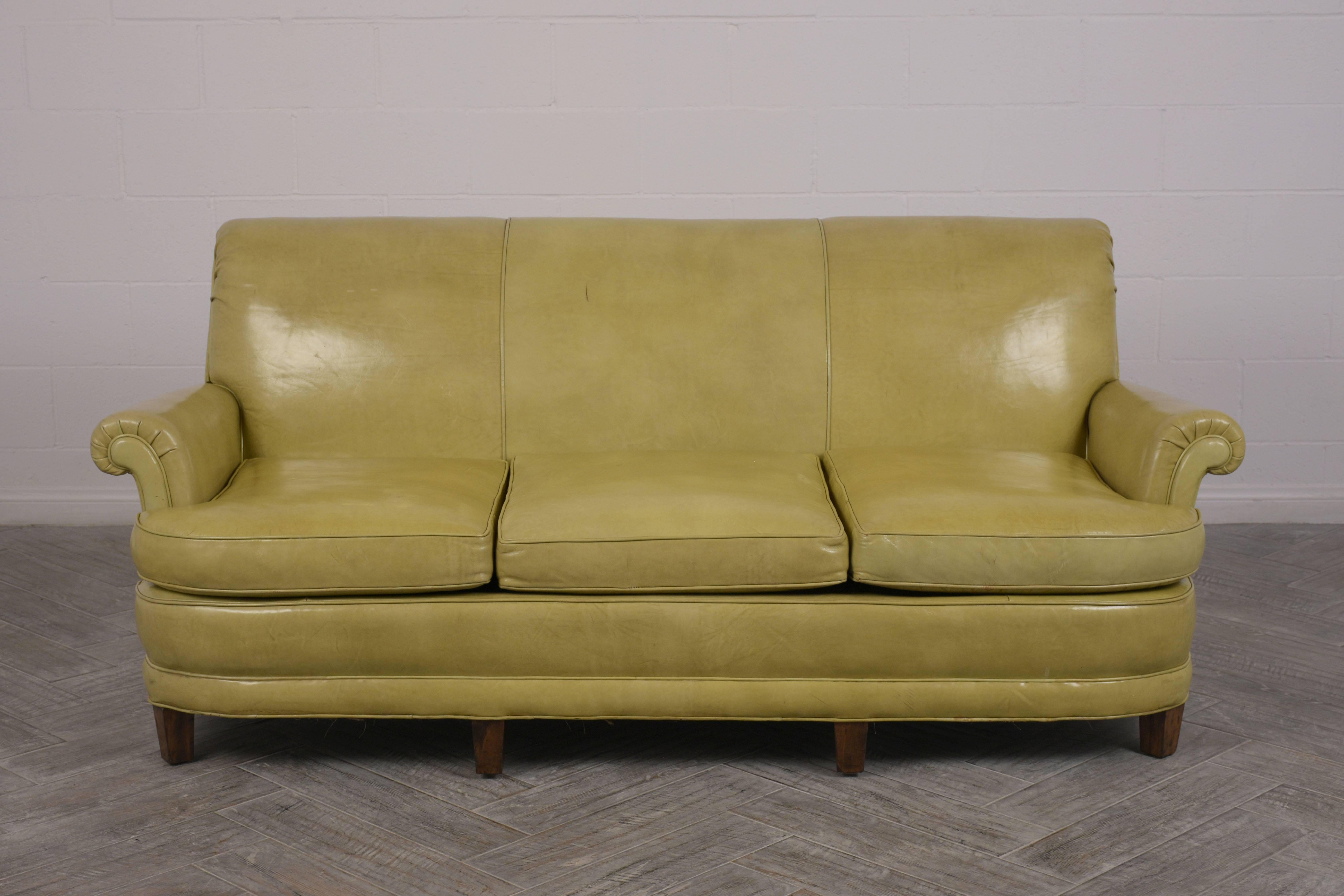 This Vintage Regency Style three-cushion Sofa has been newly restored and is upholstered in its original lemon green color leather in good condition. THe seats are very comfortable and rest on solid wood legs with a walnut finish. This 1960's