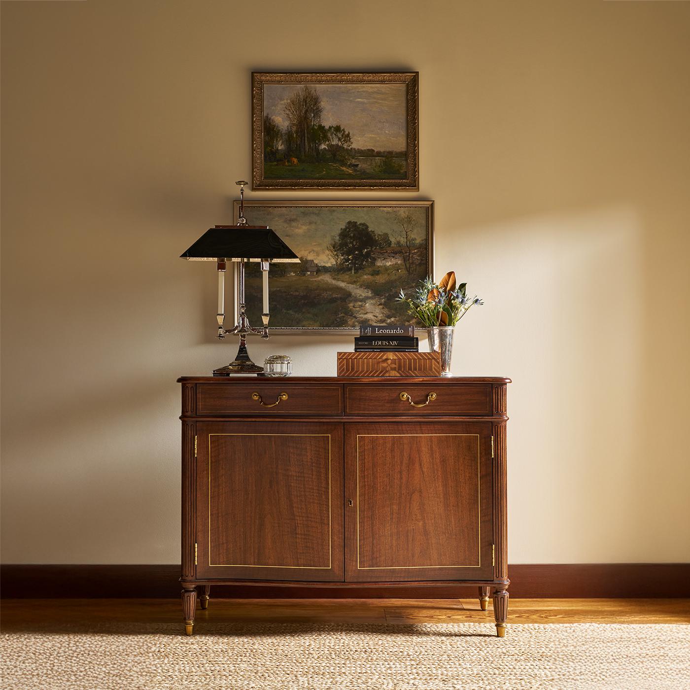 Meticulously crafted to reflect the refinement of early 19th-century English design. Made from beautifully figured wood in a warm walnut finish, it features four paneled doors with fine brass inlay and flanked by reeded quarter column stiles. The