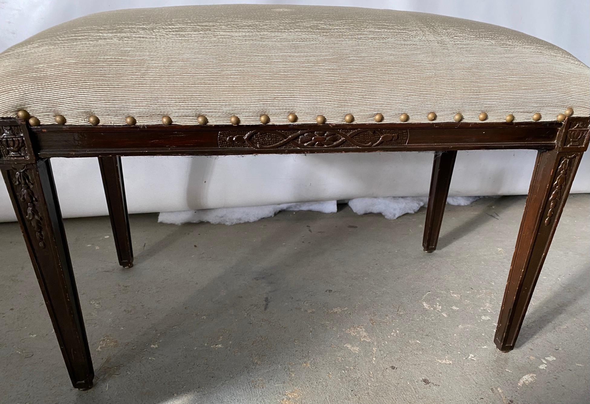 The upholstered bench can be used as a piano bench, vanity bench or extra seating when or wherever needed. Wonderful carved details giving it extra interest. Be it Sheraton, Regency, Hepplewhite or Hollywood Regency, this bench will be a wonderful
