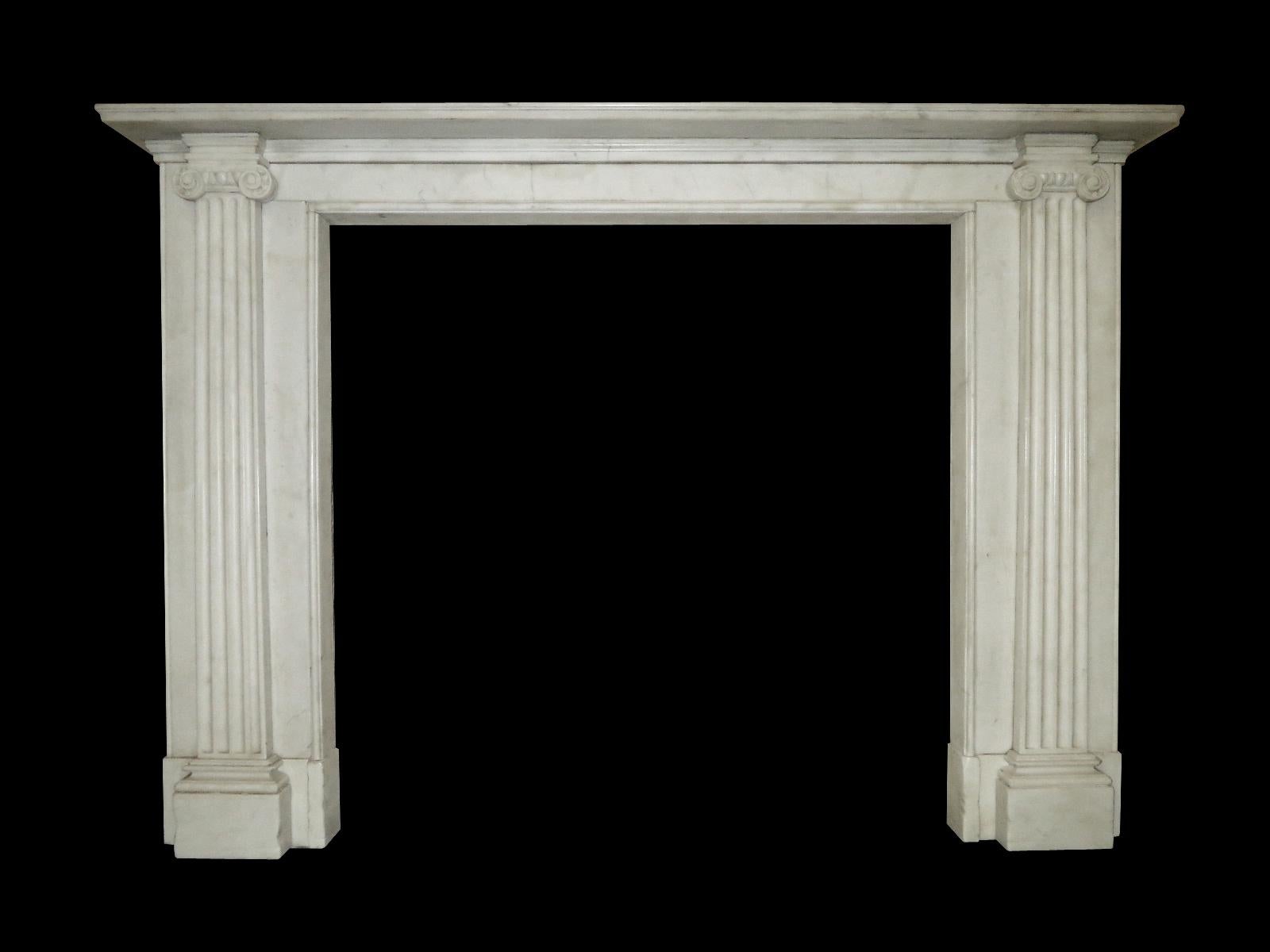 A late 20th century copy of a period piece, having fluted pilaster jambs capped with classical ionic capitals. A very slim frieze and simple moulded shelf. A large piece, very well aged and distressed. 

Measures: Opening sizes 108.5cm wide x