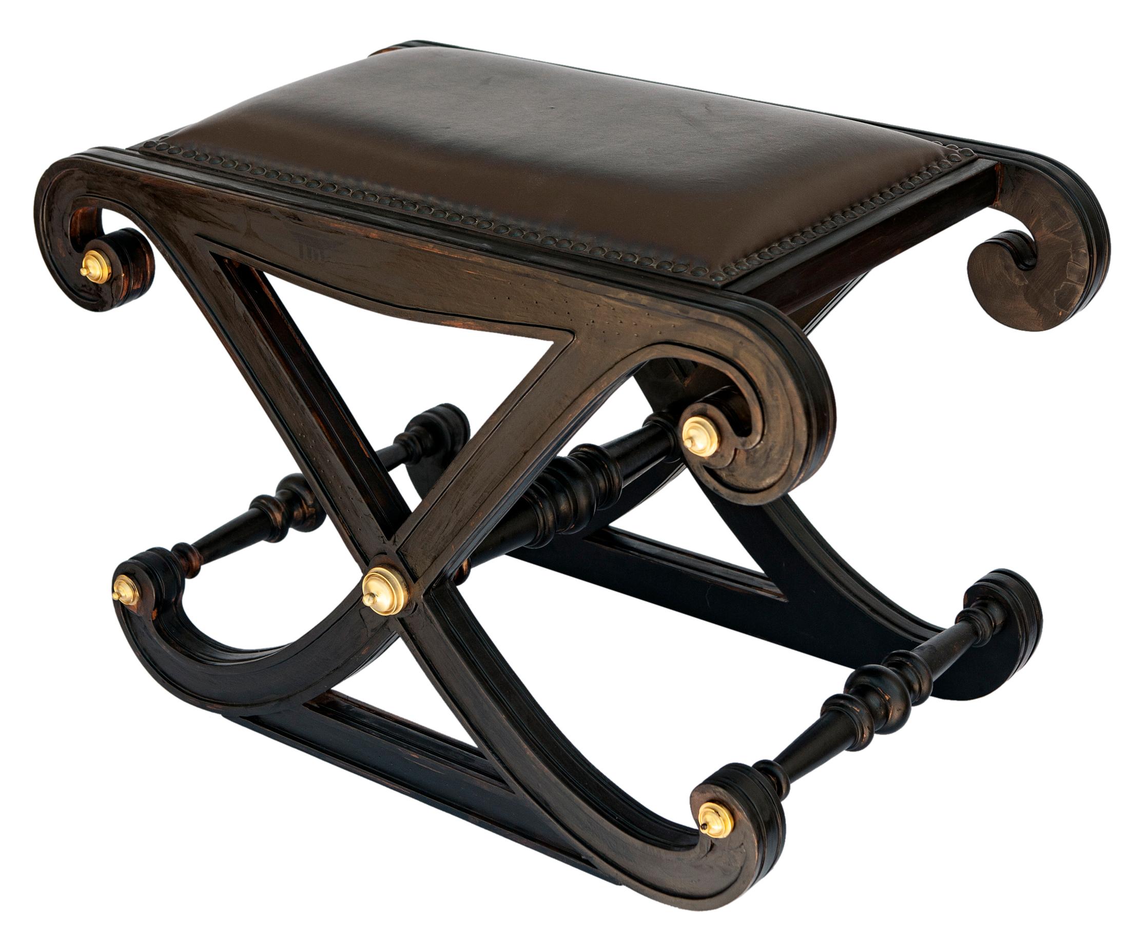 Regency style ebonized X frame stool with satin brass accents in the style of Gillows.

