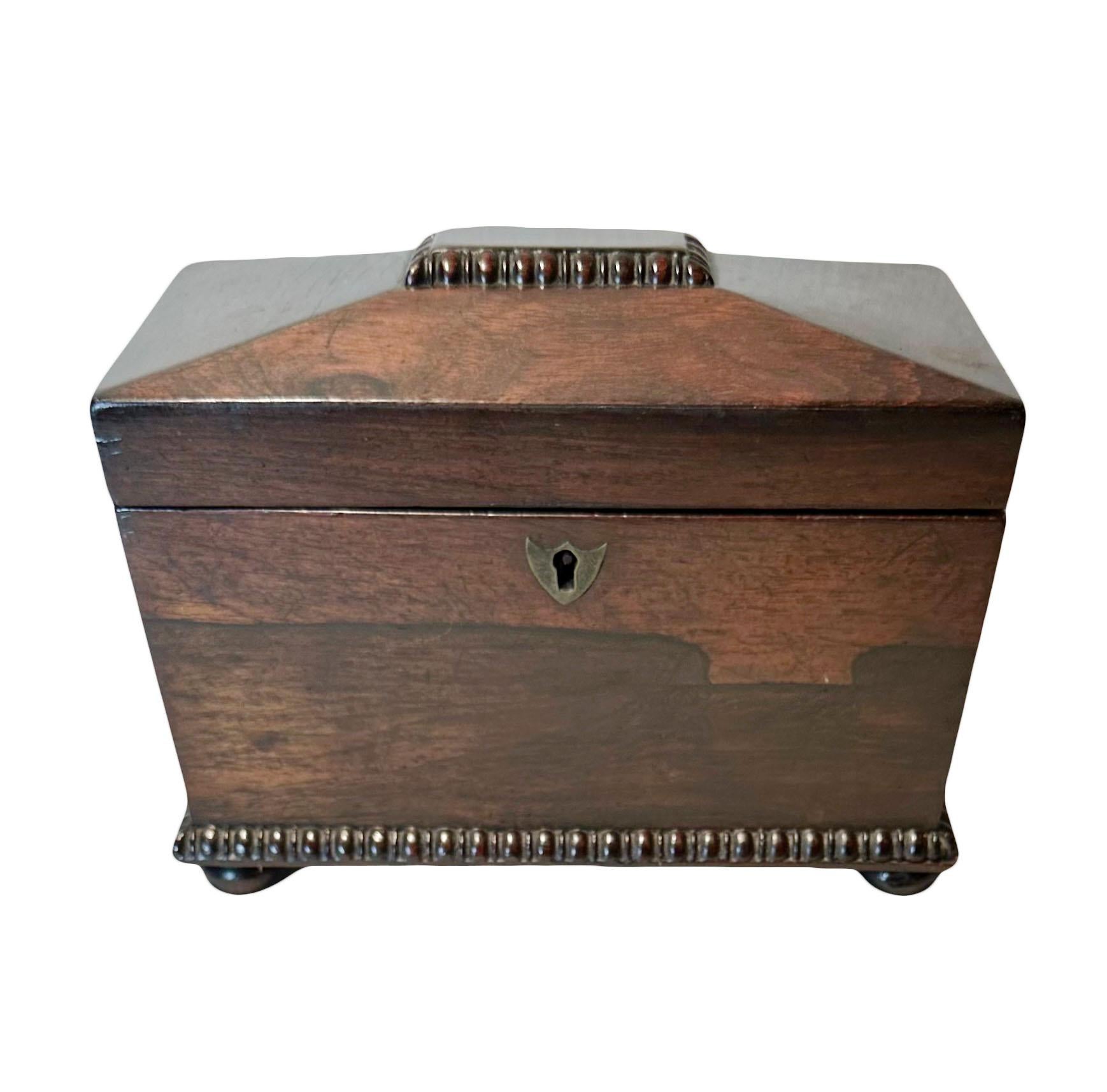 This is a wonderful English regency tea caddy in rosewood. Beautifully executed, the carving is fantastic. It’s on burn feet and its velvet lined interior is complete. The silver is gone from the tea caddy itself, but there is traces of it but In