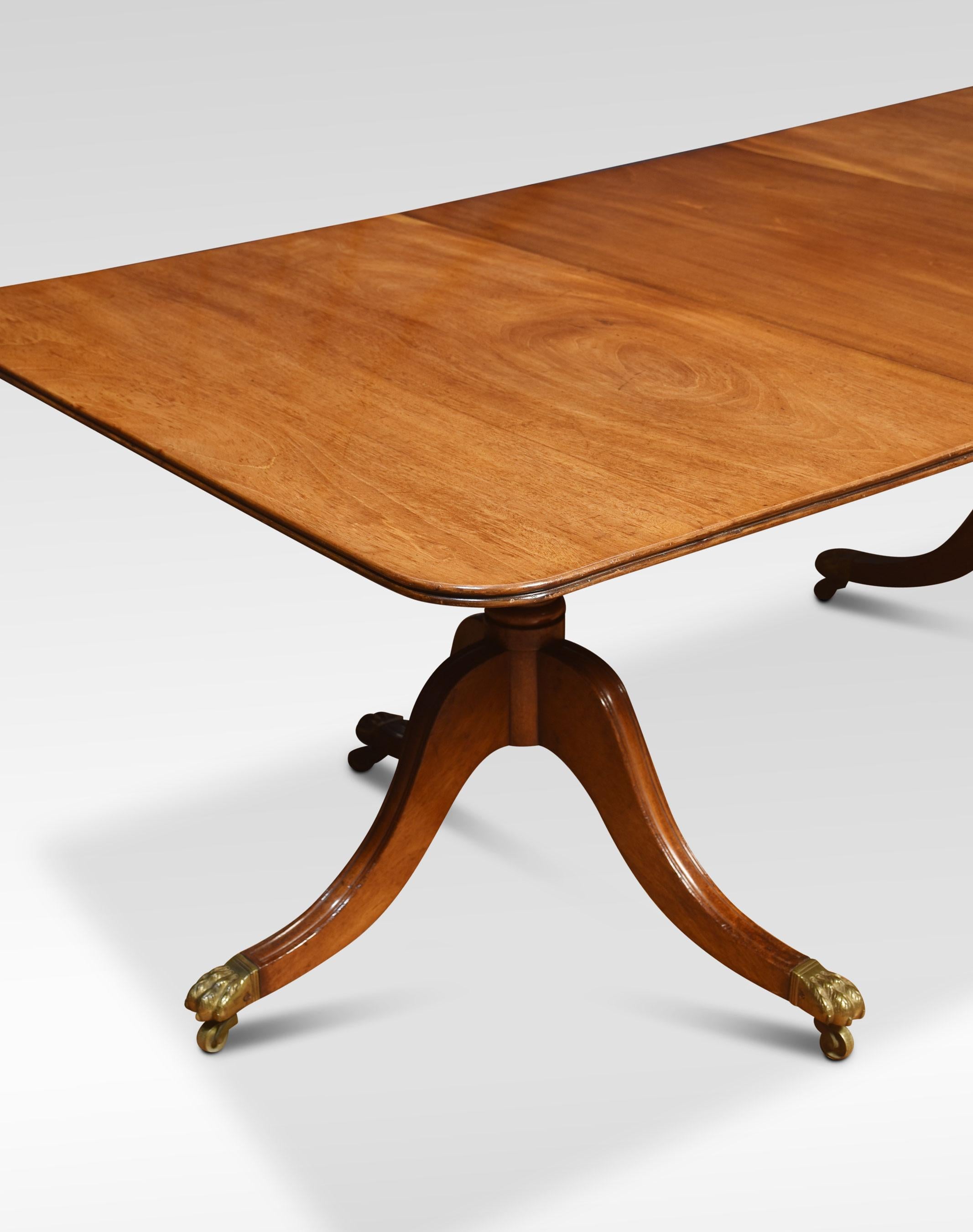 Regency dining table, the large rectangular top with rounded corners and moulded edge opening to incorporate additional leaf. Raised up on two pedestals with turned detail supported on three sabre legs terminating in brass capped paw feet and