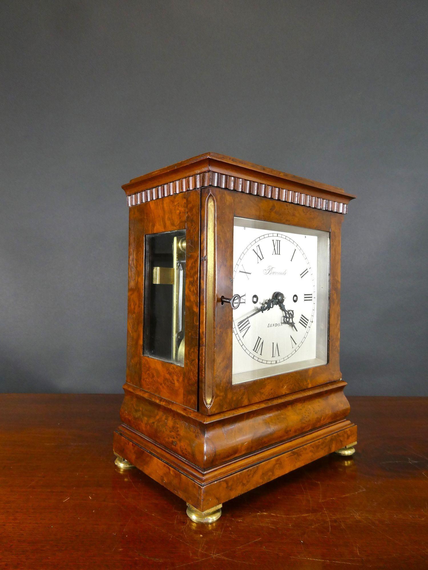 Regency Walnut Library Bracket Clock by Barrauds, London

Finely figured walnut 5 glass case with bevelled glass throughout, moulded plinth with stepped base resting on four brass bun feet. Dentil moulding decoration and canted brass corners.
Front