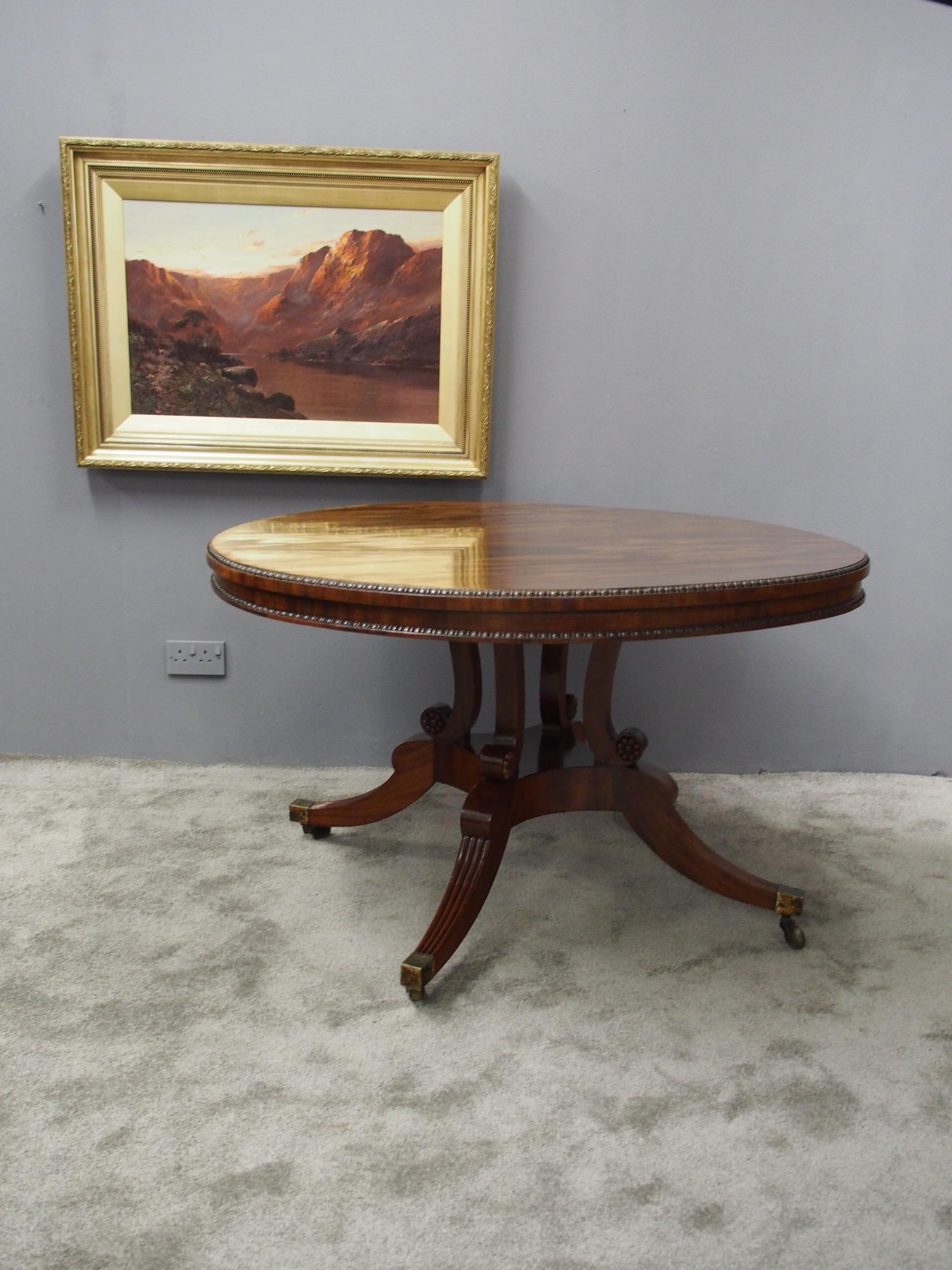 Regency mahogany breakfast table in the manner of William Trotter, Edinburgh, circa 1815. The top in flame mahogany has a beaded fore-edge and similarly beaded frieze, standing on 4 shaped uprights with carved flower heads to the sides. It stands on