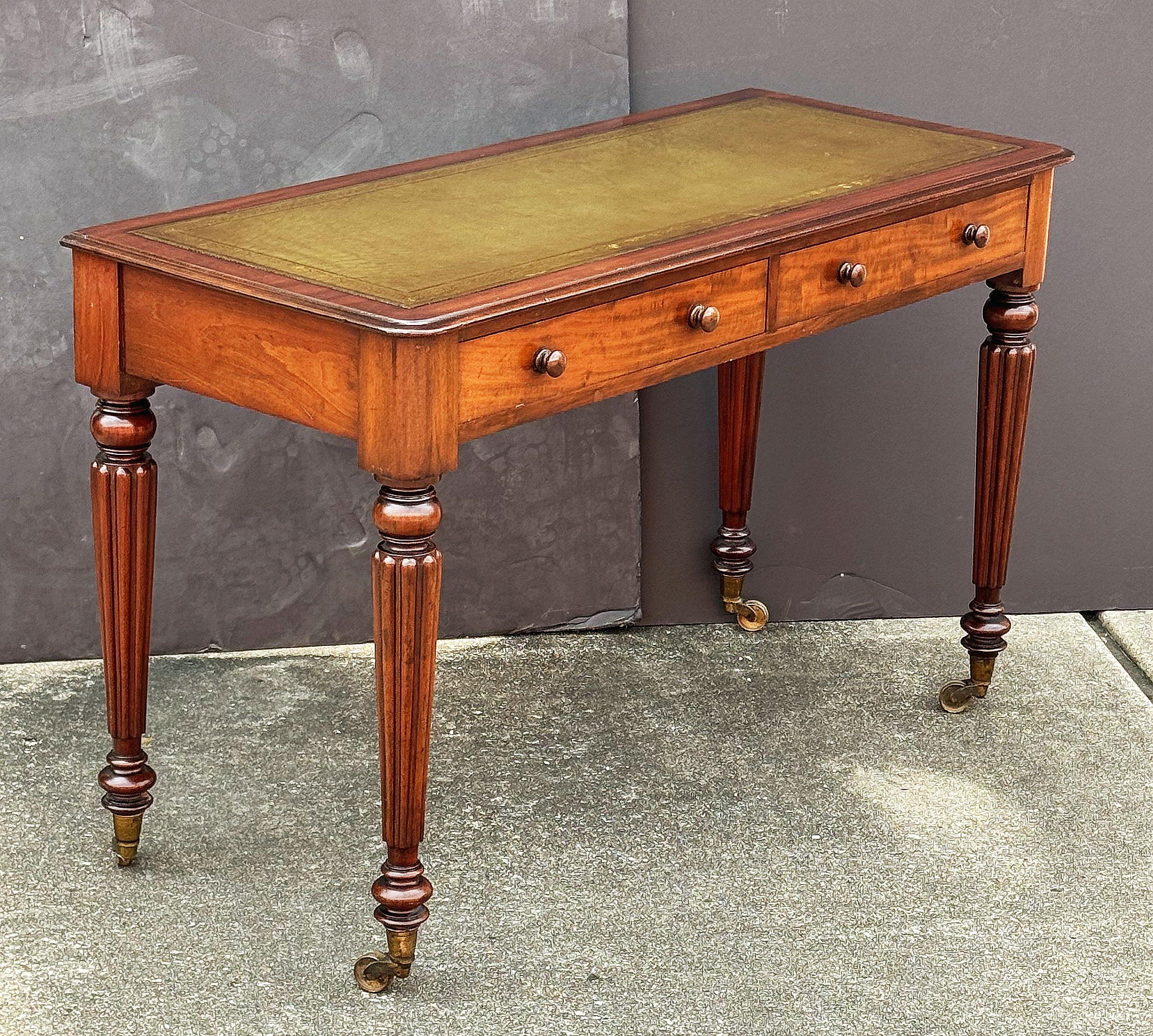 Ein feiner Mahagoni-Schreibtisch aus der Regency-Periode aus England, mit einer eingelegten, geprägten grünen Lederplatte über einem Fries aus zwei Schubladen - jede Schublade mit Knopfgriffen - und auf geriffelten Beinen mit Rollen aus Messing