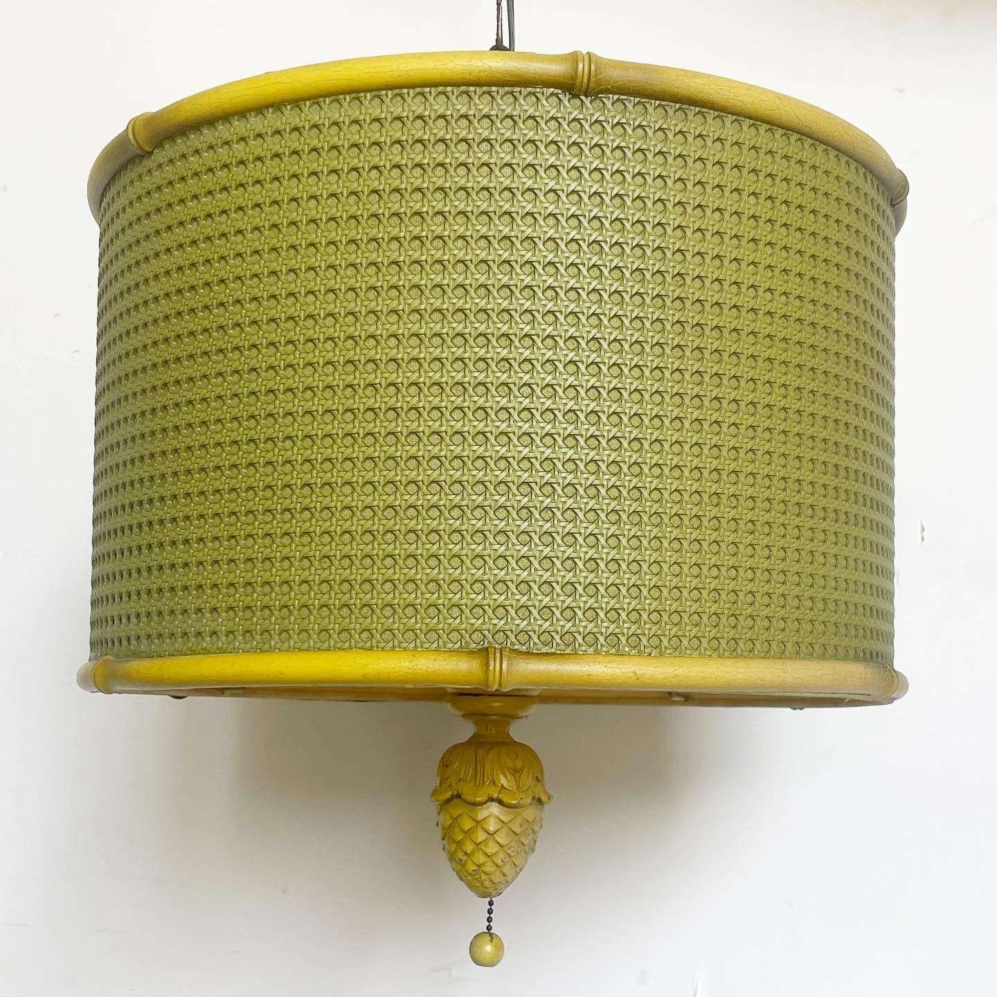 Incredible vintage regency pendant light. Features a green cane side with a yellow faux bamboo frame. Beneath the lamp is shaded by a plastic with a miniature pineapple light switch.

Chain is roughly 13 feet long.