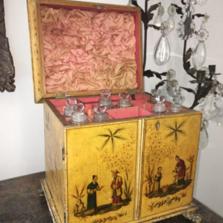 English Chinoiserie vanity cabinet with writing slope, circa 1810, a lidded top that lifts to reveal compartments holding eight crystal bottles over three drawers, the bottom being a removable writing slope containing two ink bottles. Yellow