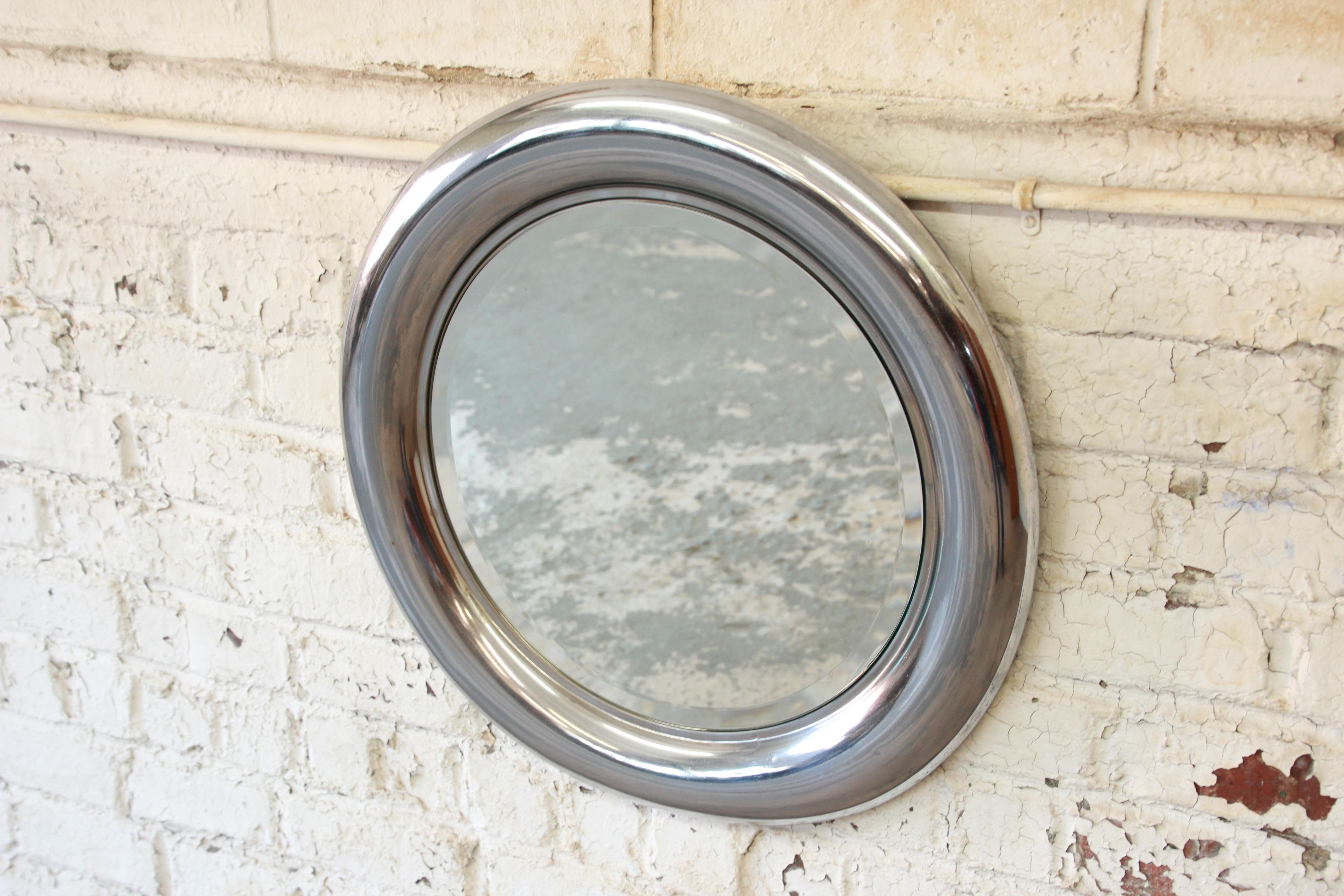 A gorgeous Mid-Century Modern round mirror produced in Italy by Reggiani. The mirror features a nice bevelled edge and a chromed metal frame. The mirror is in good original condition, with minor wear and patina from age.