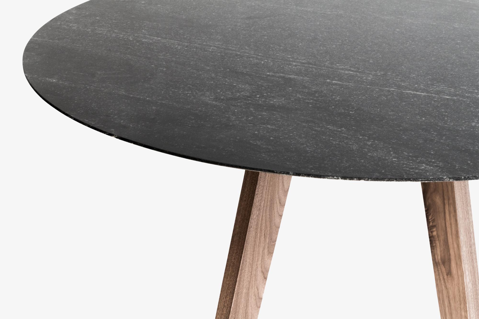 Cette table de salle à manger ronde est dotée d'un élégant plateau en granit, ce qui lui confère un caractère sophistiqué et durable. Sa base se compose de quatre pieds en bois massif, soigneusement conçus pour offrir une stabilité et une touche