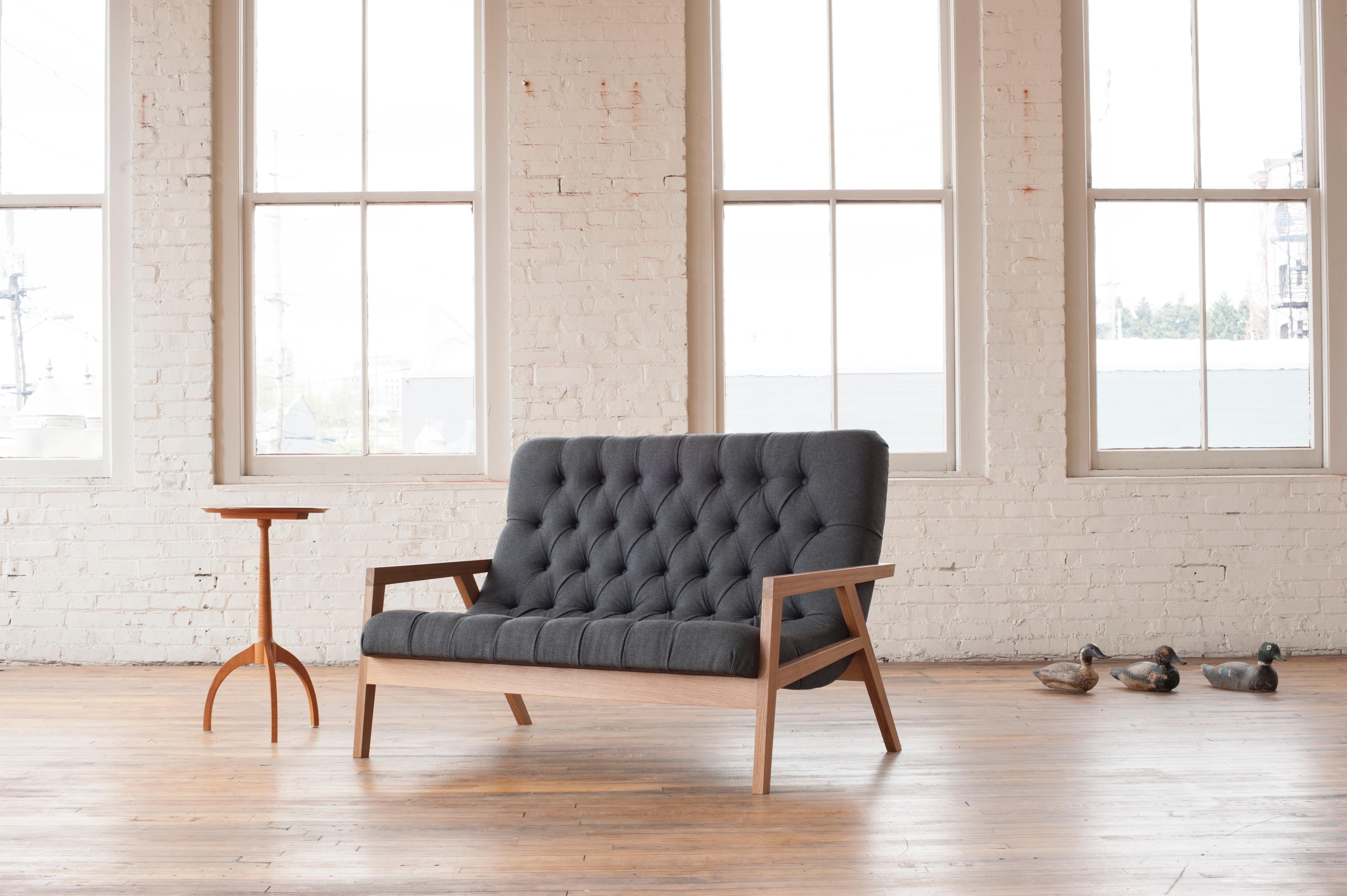 The Regina Loveseat is a handcrafted, modern contemporary loveseat with a solid wood frame that cradles a simple curved laminated plywood shell, hidden under layers of foam and traditional diamond tufted leather or wool. Incredibly comfortable, this