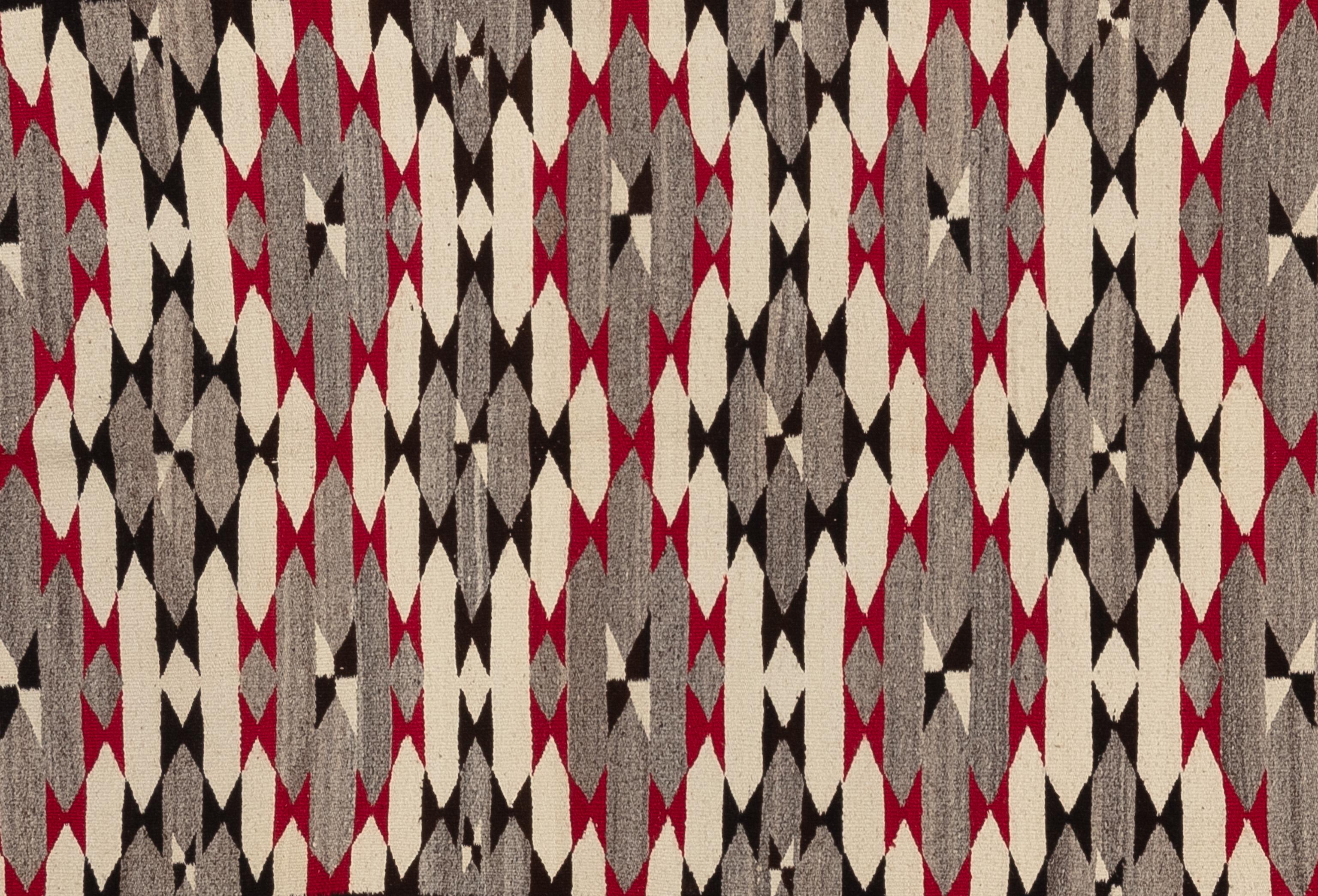 Presenting a stunning regional style rug, crafted circa 1930, that showcases exceptional artistry and traditional techniques. This beautiful piece features handspun yarns, with vibrant red accents achieved through aniline dye. The grey field of the