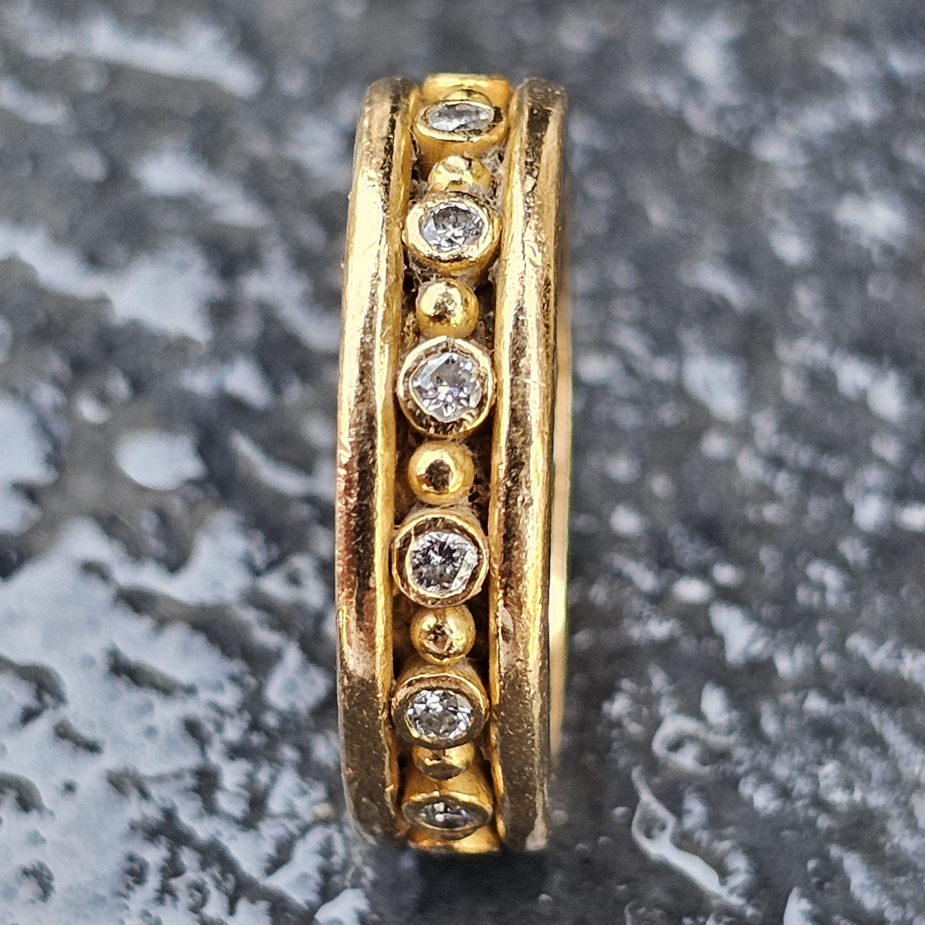 Ecco un caratteristico anello Reinstein/Ross in oro 22 carati, caratterizzato da un design audace con una fila di diamanti bianchi lungo tutto il perimetro e perline nel mezzo. L'anello misura 5,75 e presenta una finitura lucida e strutturata. I