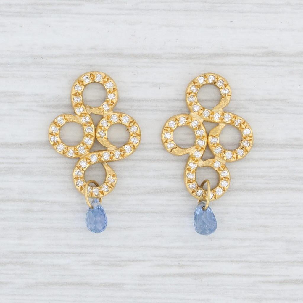 These earring enhancers are part of the Reinstein Ross arabesque collection. The charms feature swirling designs encrusted with genuine diamonds. The base of each is accented by a lovely blue sapphire briolette. These beautiful earring charms have a