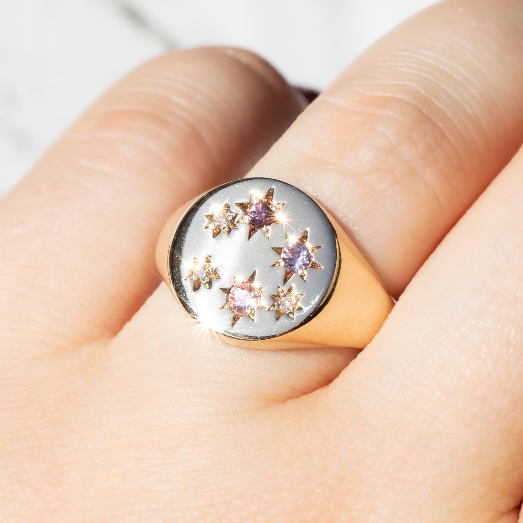 Forged in 9 carat white gold, this adorable reinvented vintage ring sees a gleaming band widen to a circular top set with faceted round sapphires in shades of pinks and purples and two shimmering round brilliant cut diamonds. Her name is Emmeline,