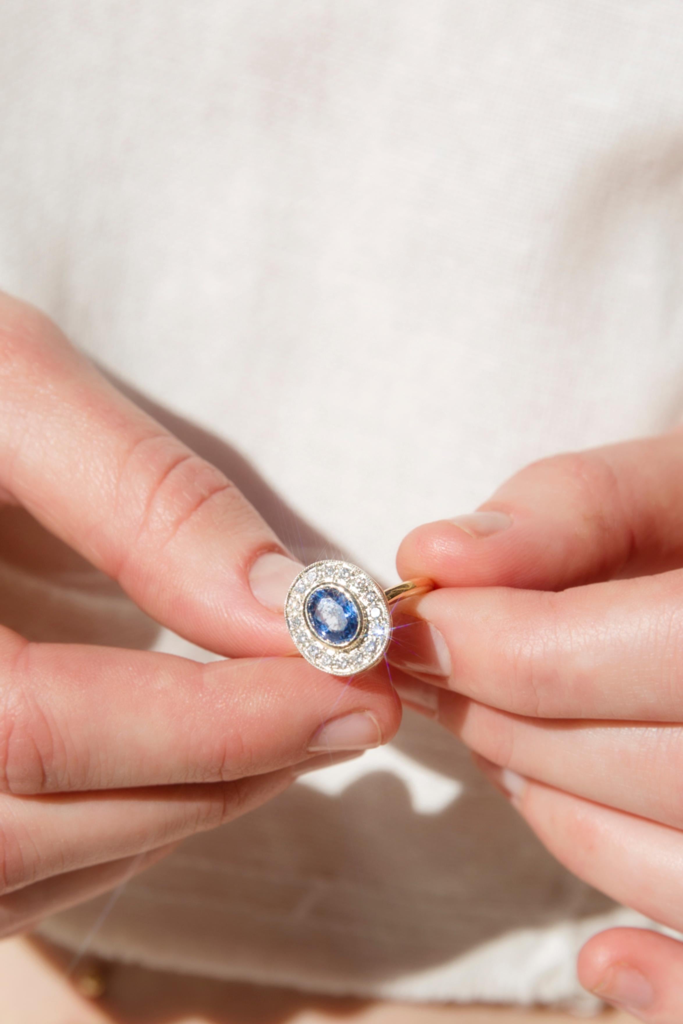 Lovingly reinvented in 18 carat yellow gold The Avril Ring holds a stunning oval bright blue Ceylon sapphire in the embrace of sparkling round brilliant cut diamonds. Raised to anticipate light dancing under and through the setting and worn to