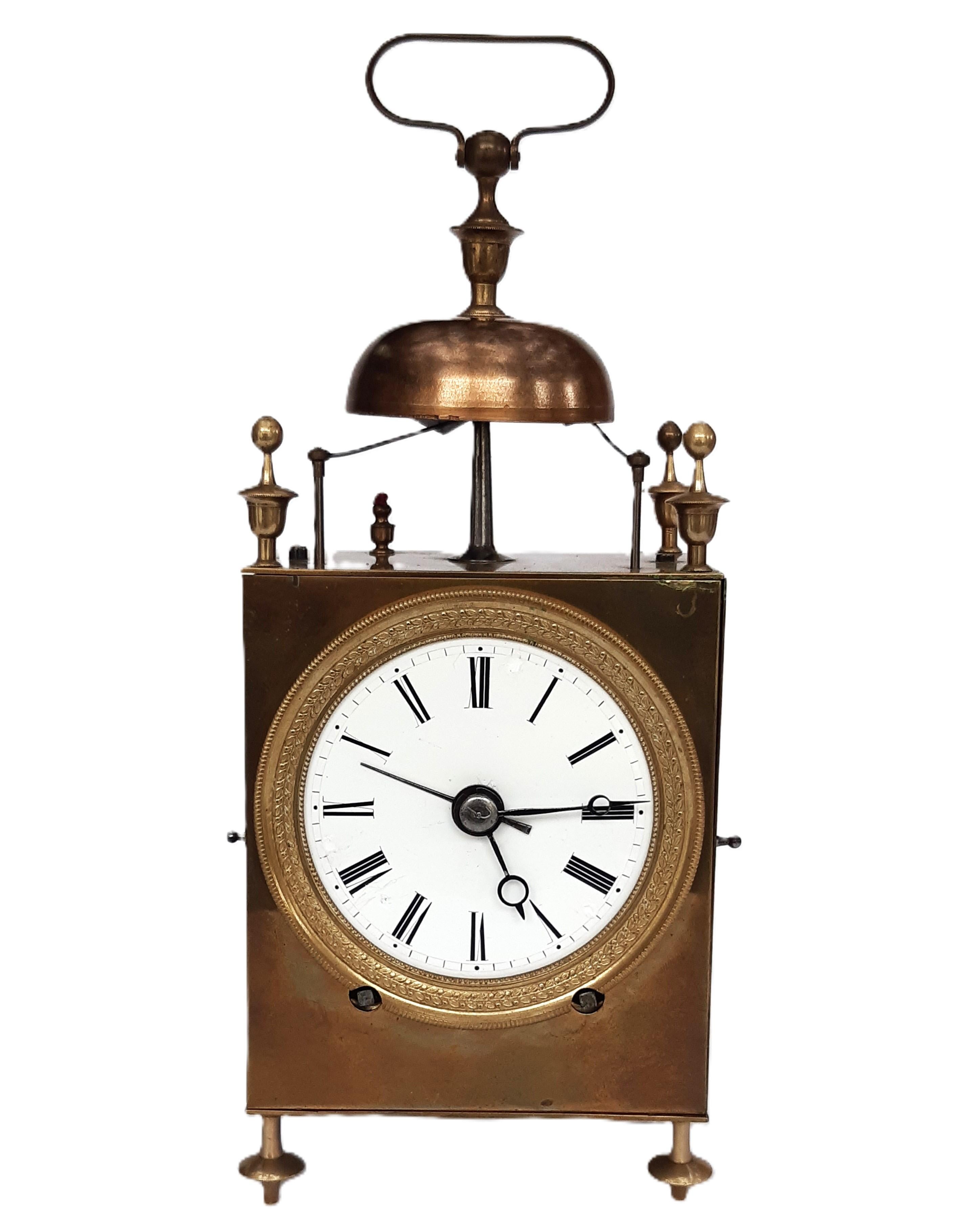 Antike französische Reiseuhr, bekannt als „Capucine“-Uhr. Diese Uhren stammen typischerweise aus der Zeit um 1800 bis 1825. 
Sie zeichnet sich durch ein hochrechteckiges Messinggehäuse auf vier Füßen aus, gekrönt von einer Glocke und einem