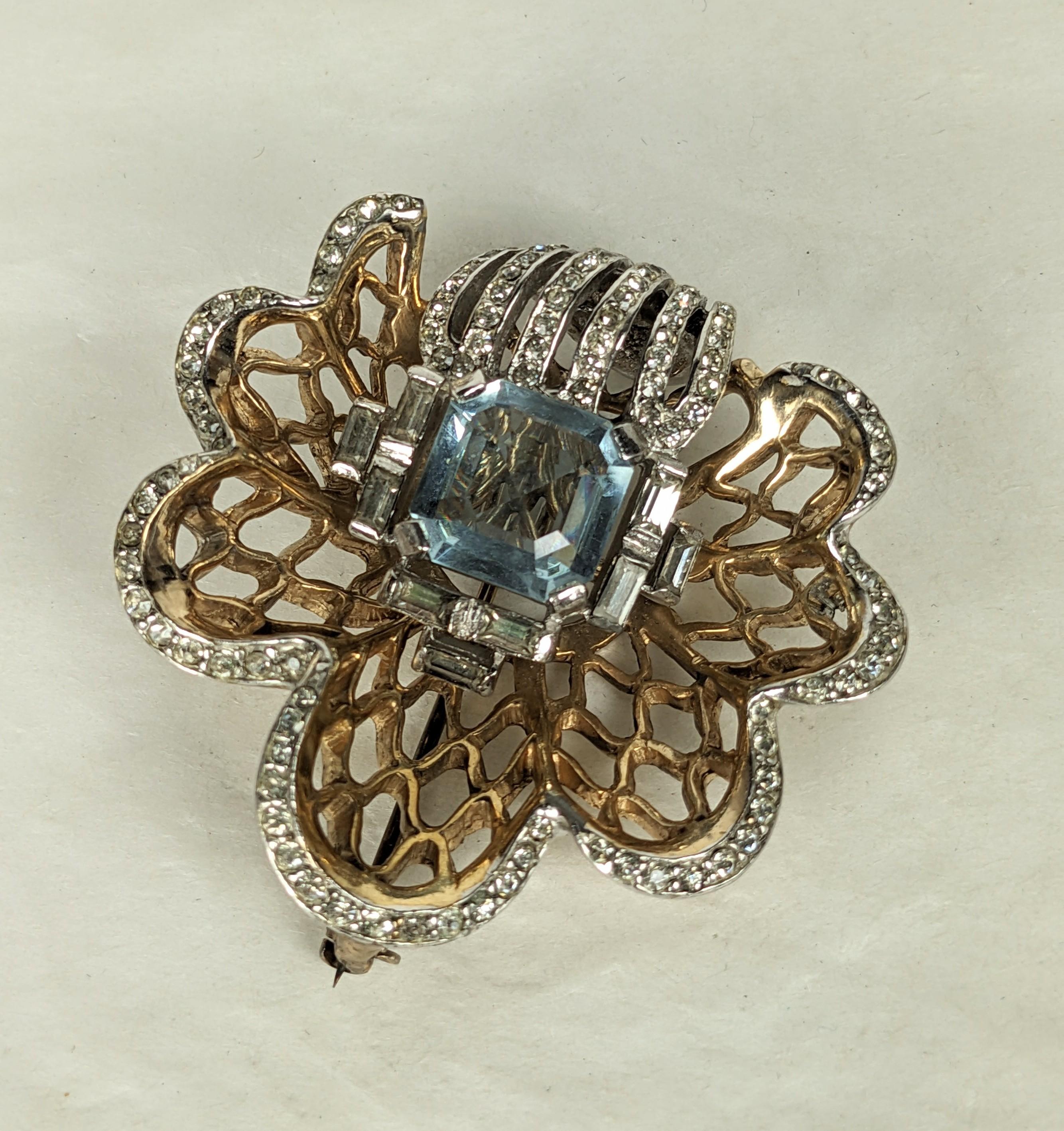 Reja Retro brooch of  a focal faux pale blue amythest square cut stone with crystal baguette accents and crystal rhinestone pave. Set into a dimensional Retro fretwork shell of pale pink gold plate over rhodium plated base metal. Very Good