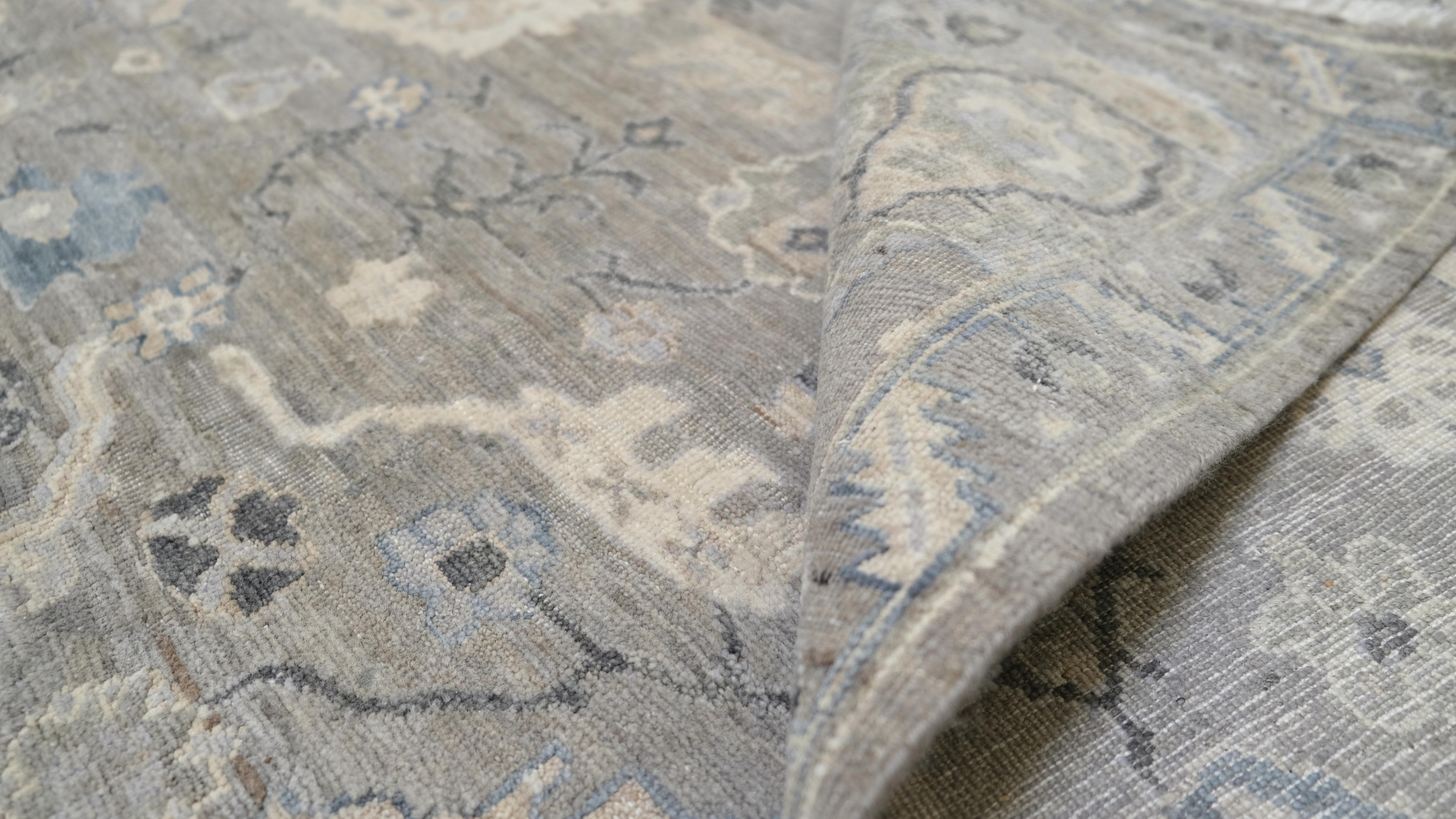 Introduce una elegancia atemporal en tu hogar con esta alfombra de lana anudada a mano, que muestra un refinado diseño floral tradicional. Realizada en una sofisticada paleta de tonos grises, marfil y azul suave, esta alfombra combina detalles