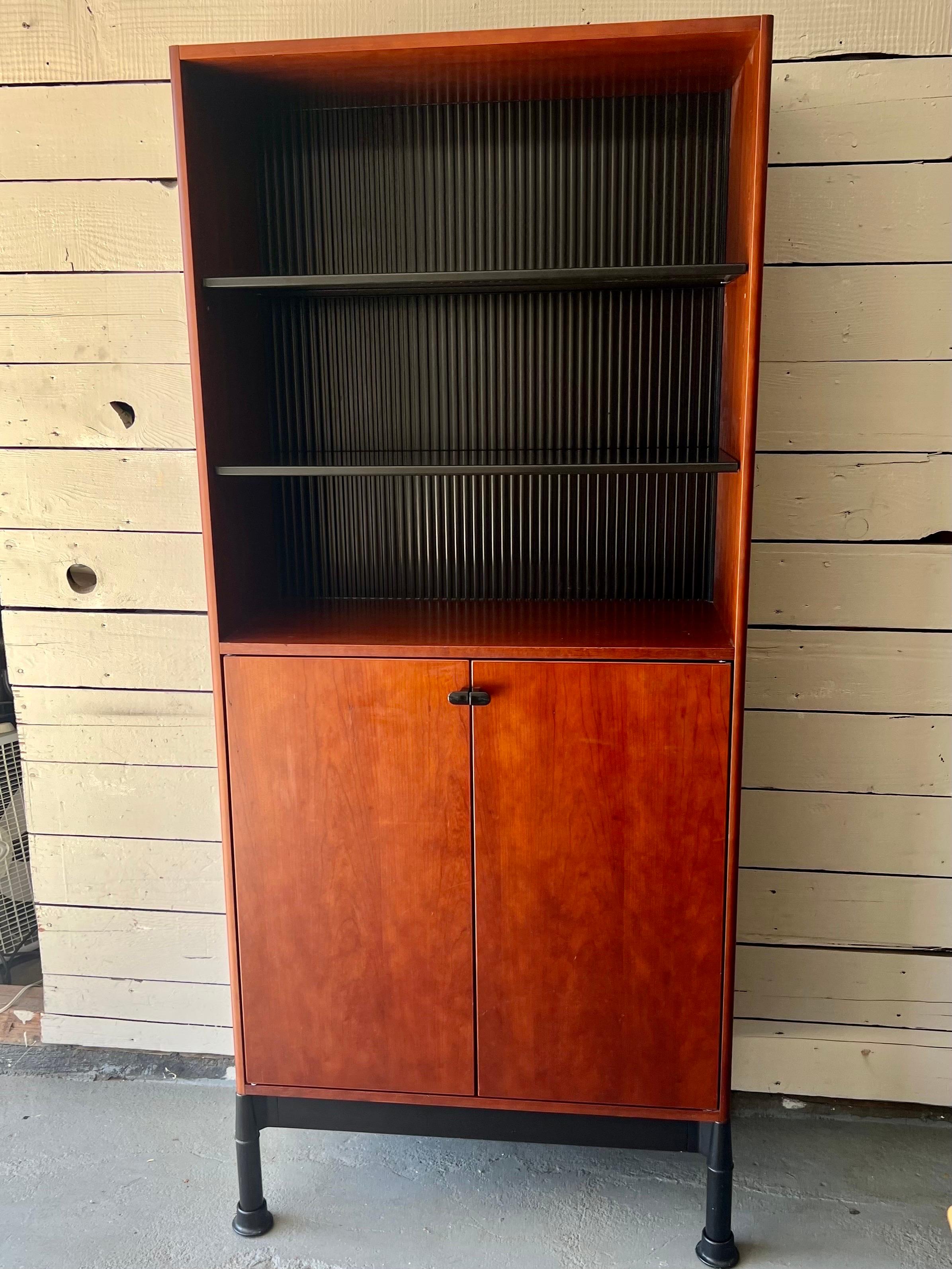 Designed by Geoff Hollington as part of his Relay Office Series for Herman Miller, this fantastic piece is comprised of two parts, a lower cabinet behind doors and open air upper shelving.  The bottom cabinet hides away one adjustable cherry wood