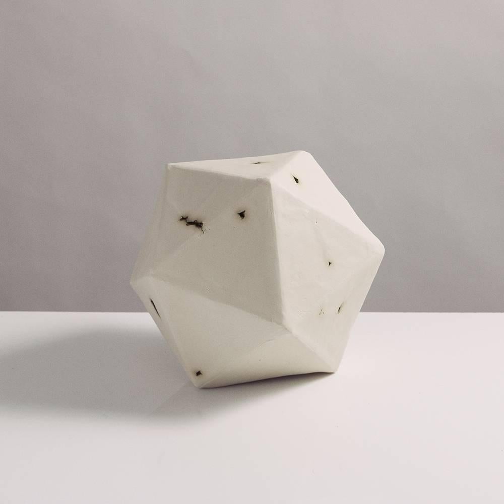 This sculptural geometric icosahedron is handcrafted from slabs of unglazed white porcelain with highly individual black oxide burnout detailing, giving each of its 20 sides a unique textural matte finish. The organic texture contrasts with the