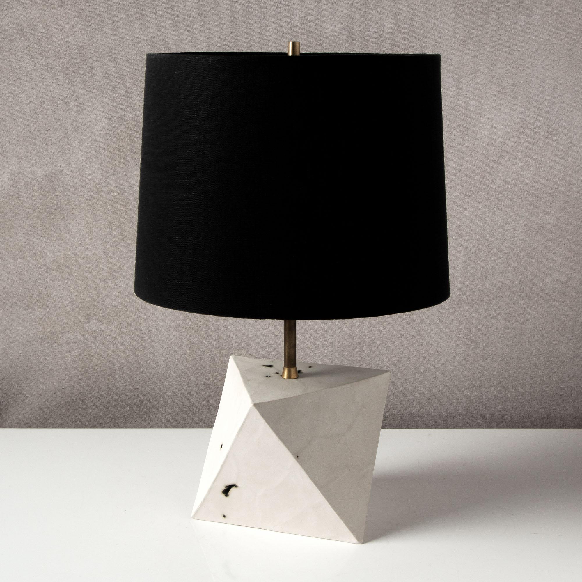 This sculptural geometric lamp is and crafted from slabs of unglazed white porcelain with highly individual black oxide burnout detailing, giving each of their facets a unique textural matte finish. The organic texture contrasts with the clean