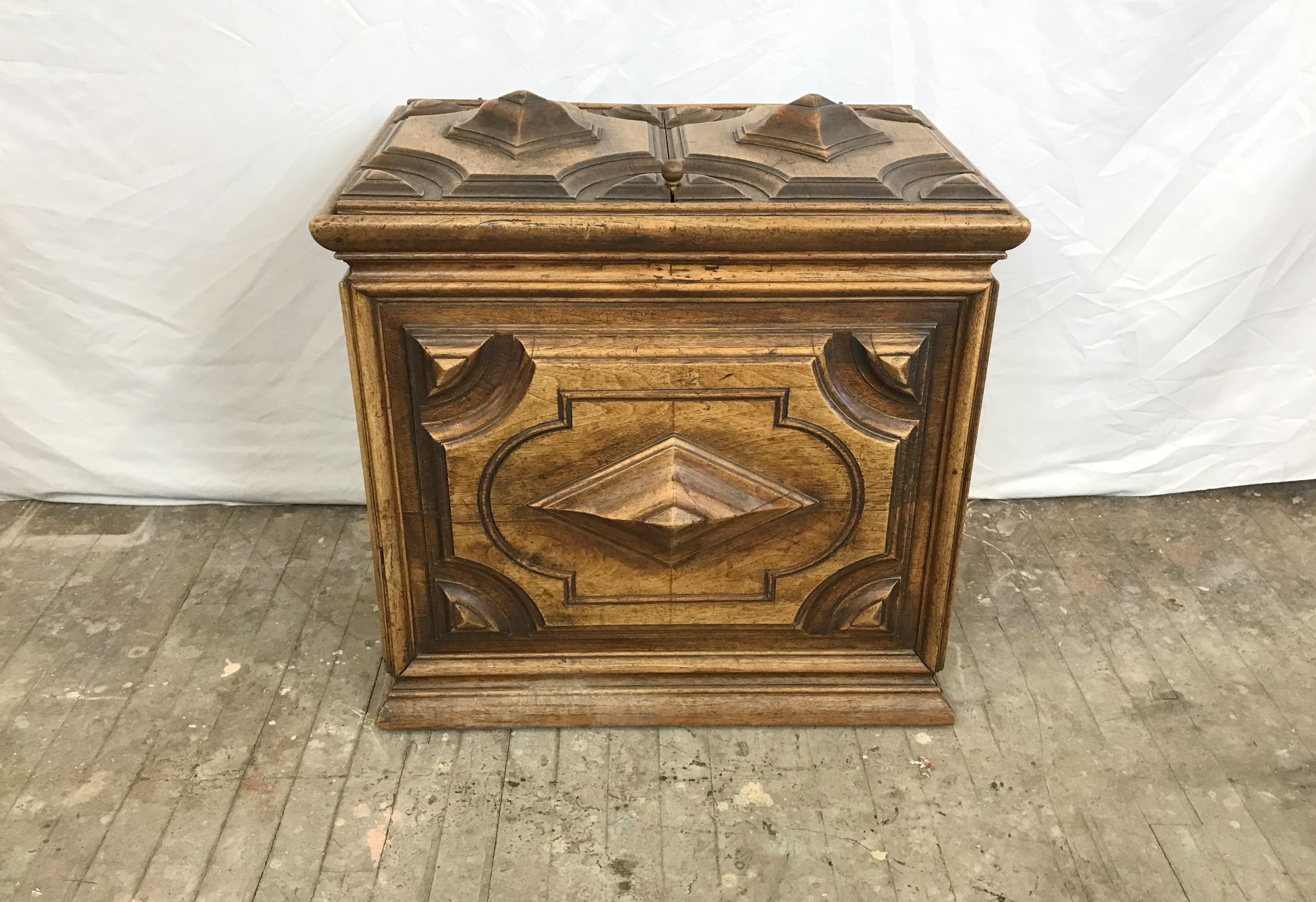 An extraordinary French storage box, made of walnut, dating to the 1700s. It's accessed from above via a hinged top with hand forged iron work. It's decorated with carved geometric raised panels. It's a great piece and came from the estate of