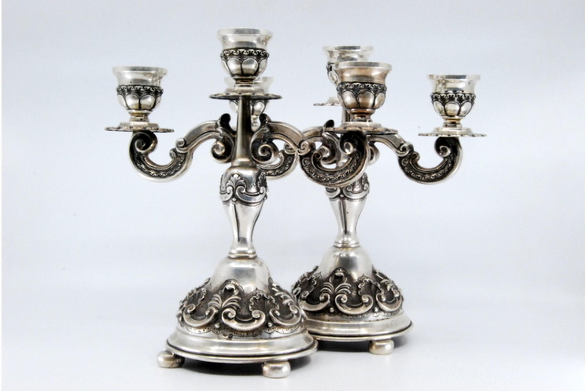 Description: Silver candelabra in relief with shells in the style of D. João V, with three lights, resting on circular bases with four feet. Metal: Silver. Origin: Portuguese. Mark: Porto open-wing eagle. Weight: 862.24 grams. Dimensions: 21.5x22cm.