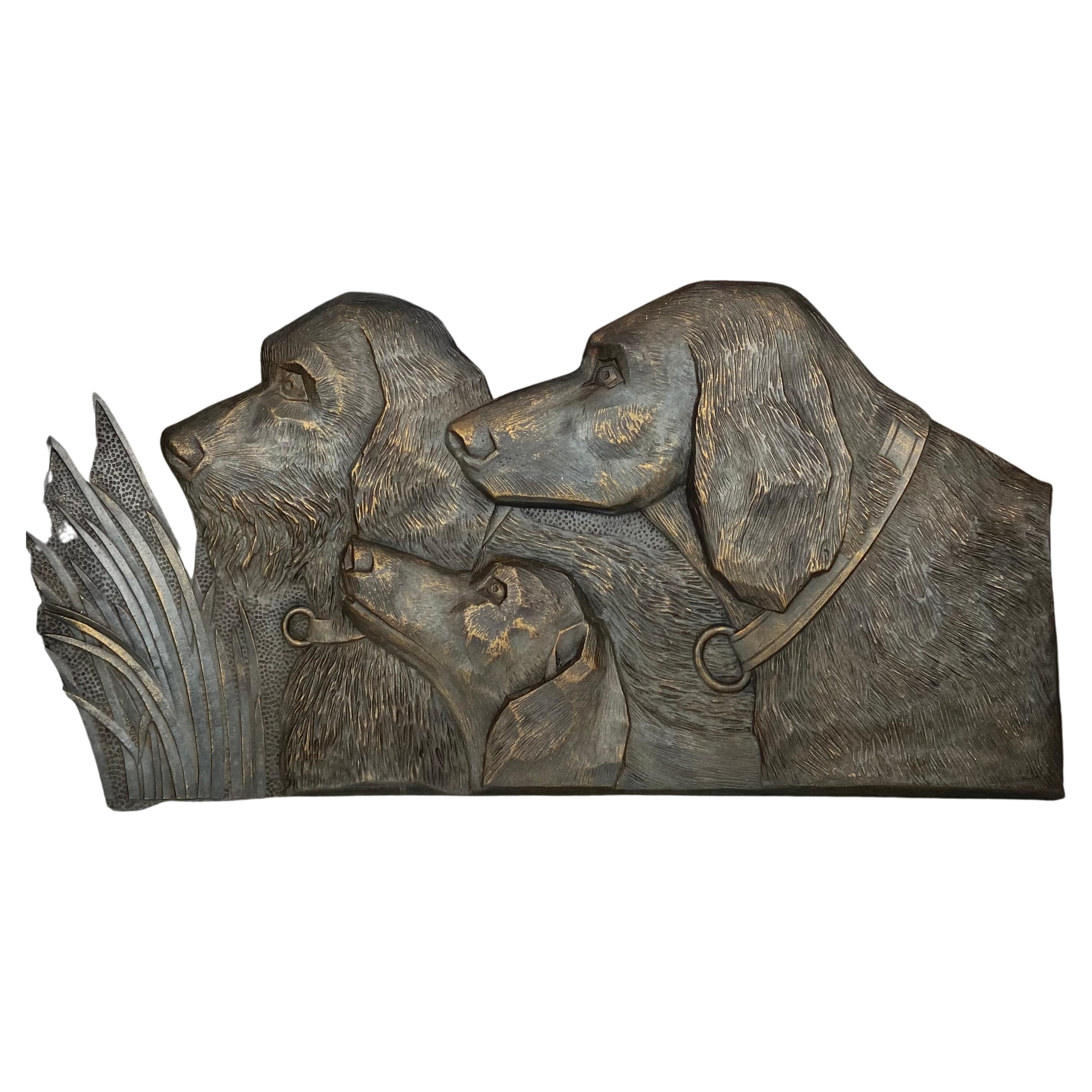 Wall plate in relief with 3 dog's heads. Three different dog breeds, three different hunting dogs. The relief is in bronzed eternite, with 4 holes to hang up.