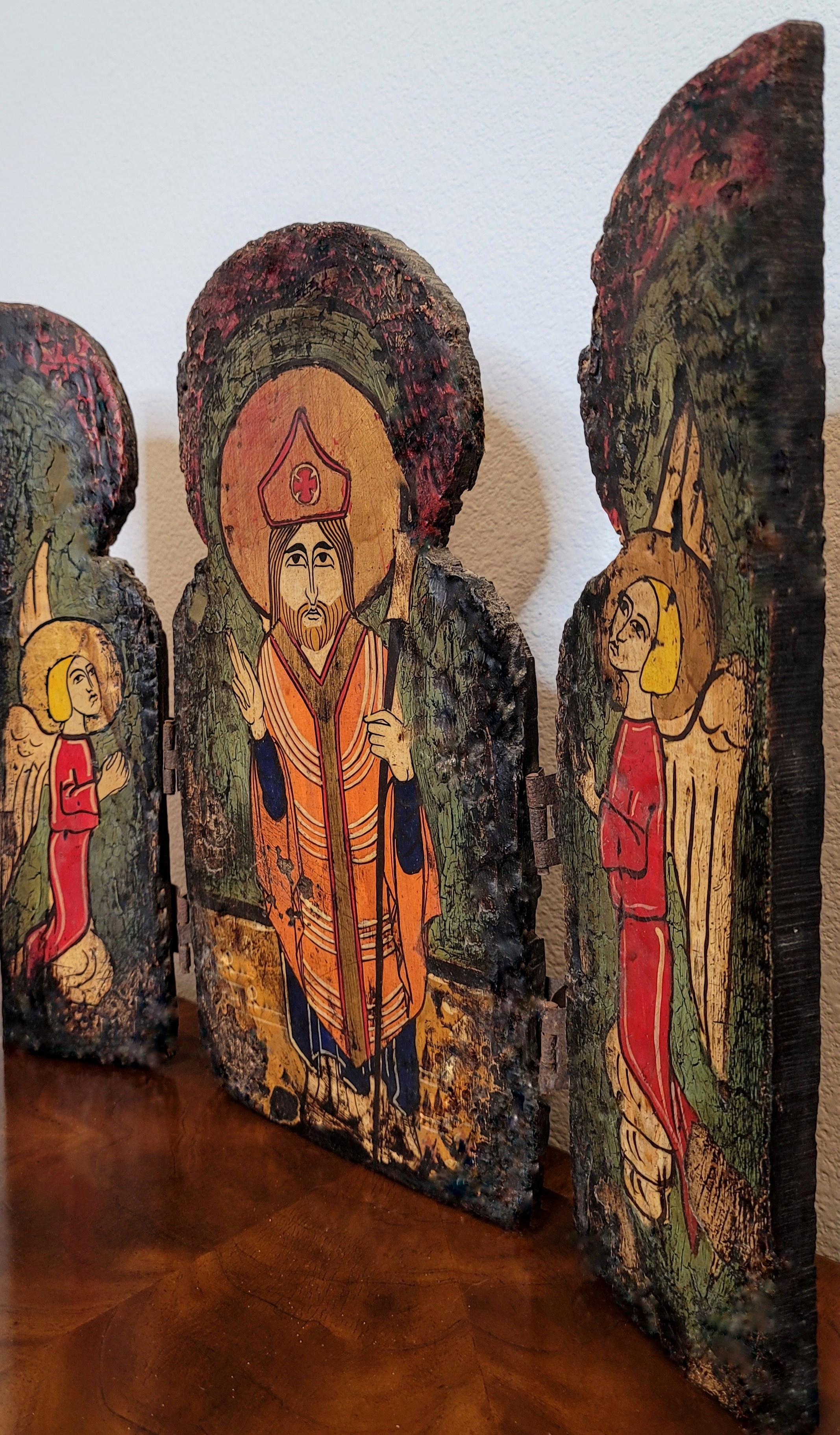 Rustikales religiöses Ikonentriptychon mit drei geschnitzten Holztafeln, 20. Jahrhundert, bestehend aus drei stark patinierten, mit Scharnieren versehenen Holztafeln, verziert mit Paketvergoldung und reicher polychromer Bemalung, die einen Heiligen