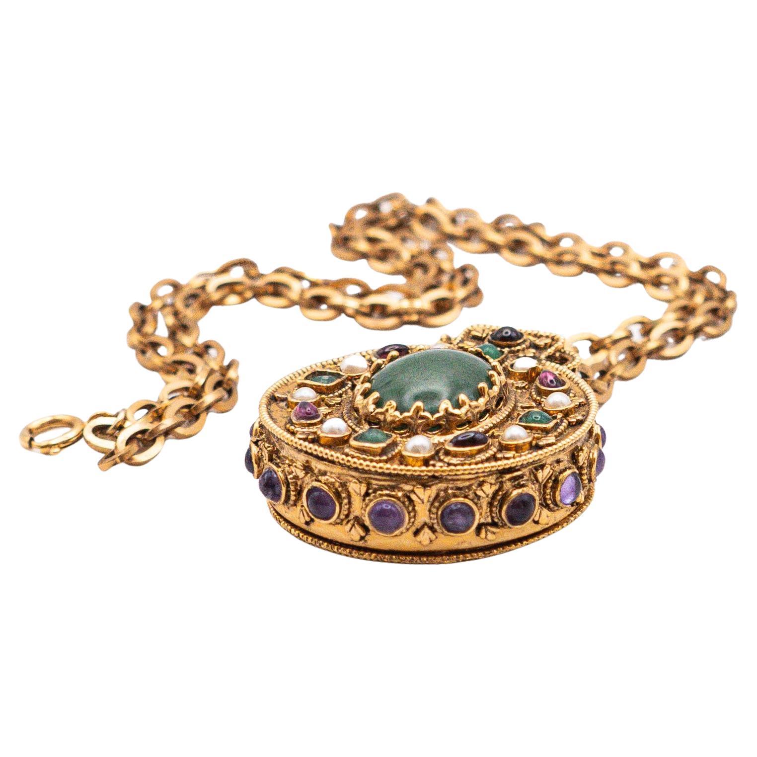 CHANEL Made in France by ROBERT GOOSSENS 

Gold metal necklace with reliquary pendant decorated with green and red glass paste cabochons and small pearly beads - signed Chanel
Height 33cm

Goossens is one of the most prestigious names in Haute